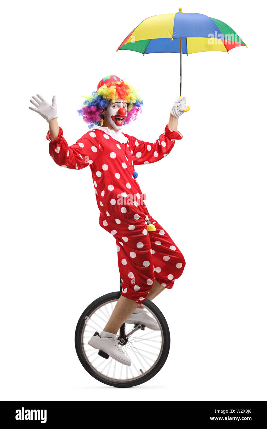 Full length shot of a clown riding a unicycle and holding an umbrella isolated on white background Stock Photo