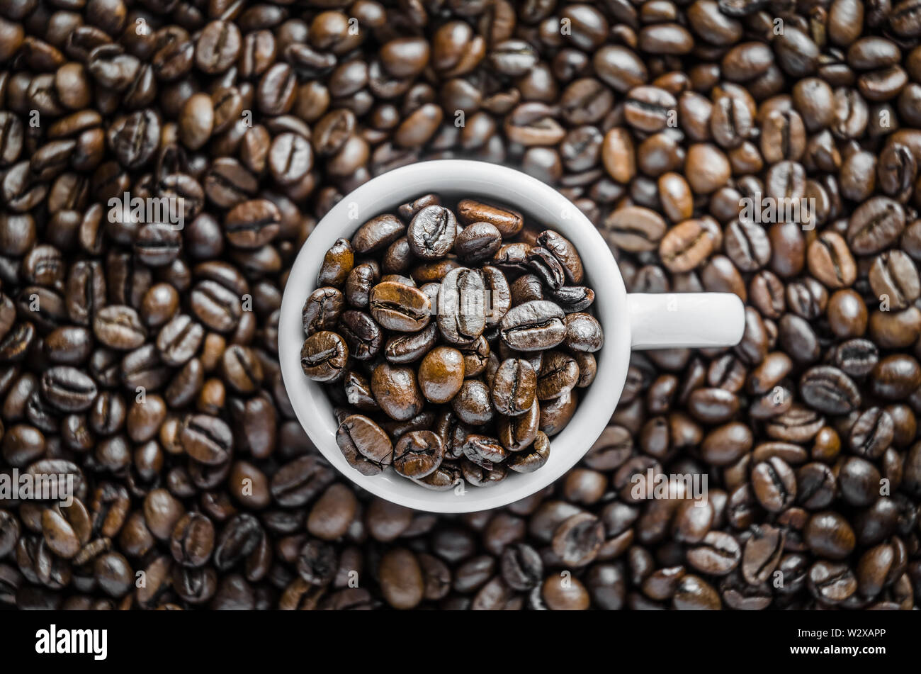 Closeup still life of roasted espresso coffee beans in a cup, flat lay