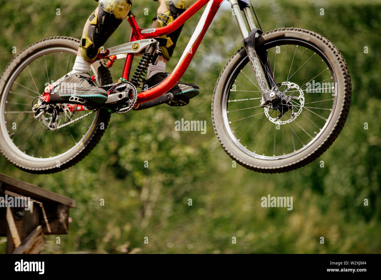 wheels downhill mountain bike jump in drop on background of green forest Stock Photo