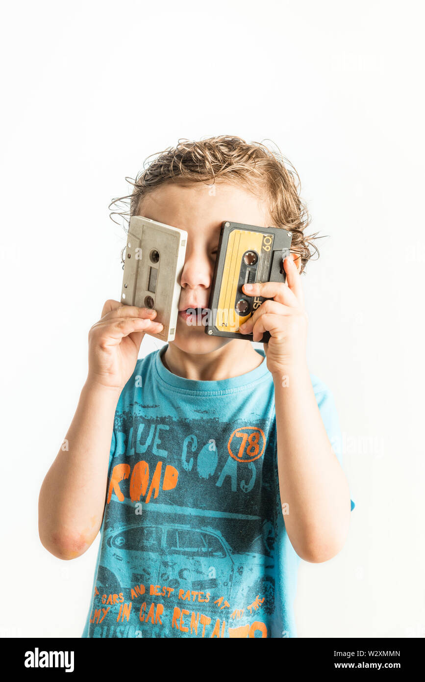 Child looking through the holes of a cassette tape on white background. Stock Photo