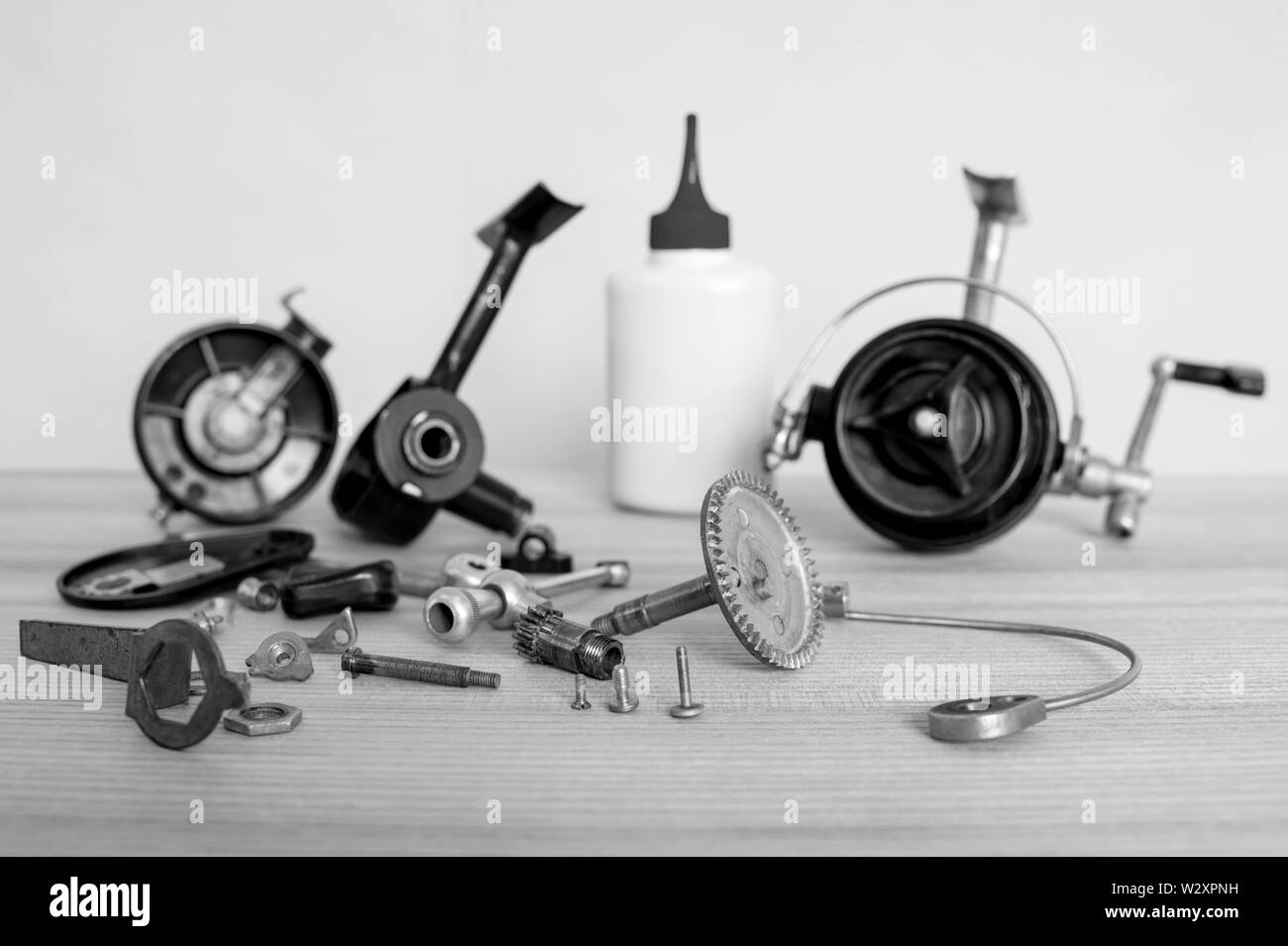 A fishing spinning reel as a whole and a second similar completely disassembled. Black and white image. Stock Photo