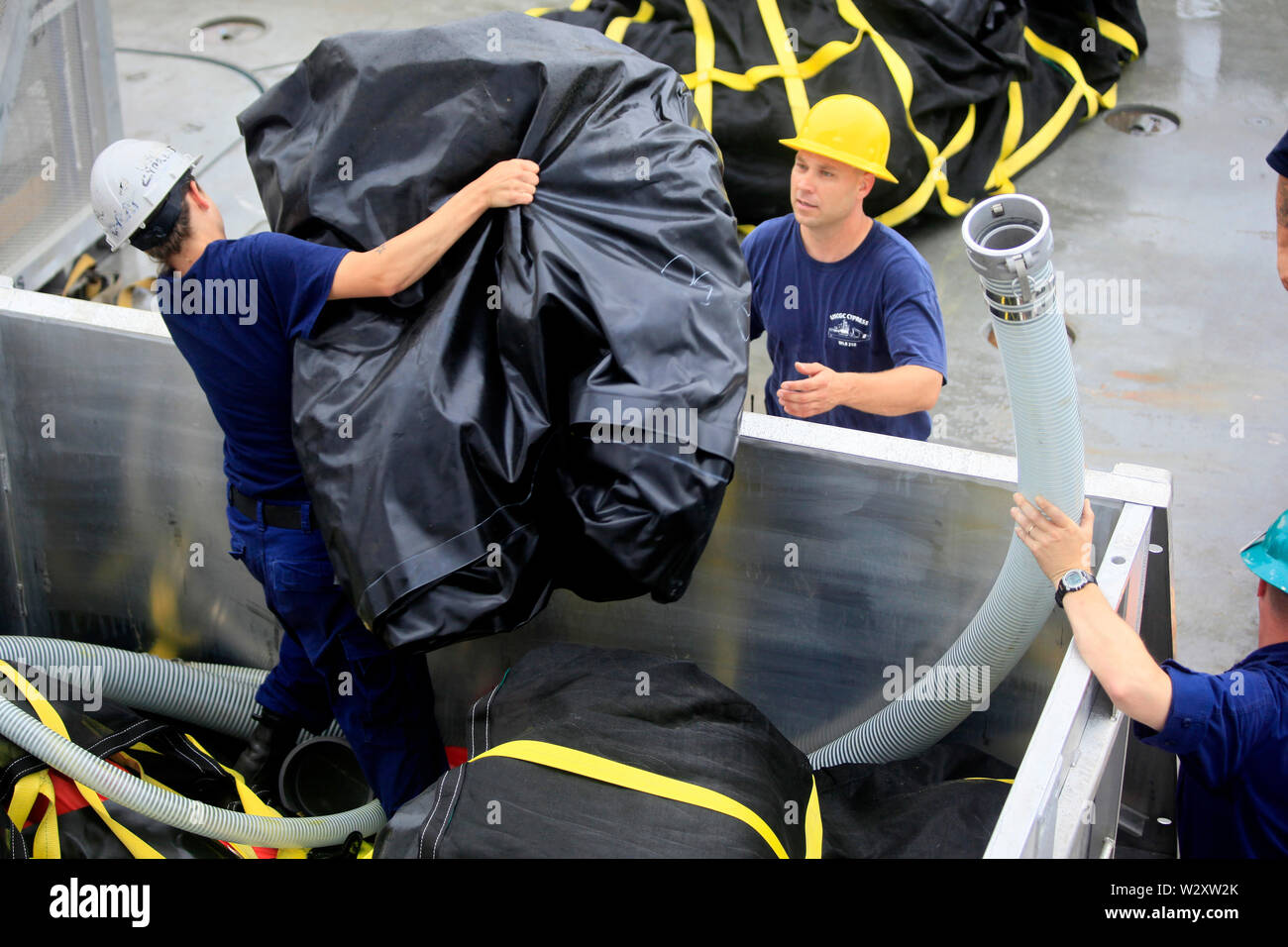 The crew onboard the USCG Cypress Cutter load equipment for skimming of oil spill. The ship is joining USCG Oak in an effort to skim some of the oil slick coming from the Deepwater Horizon oil spill. Stock Photo