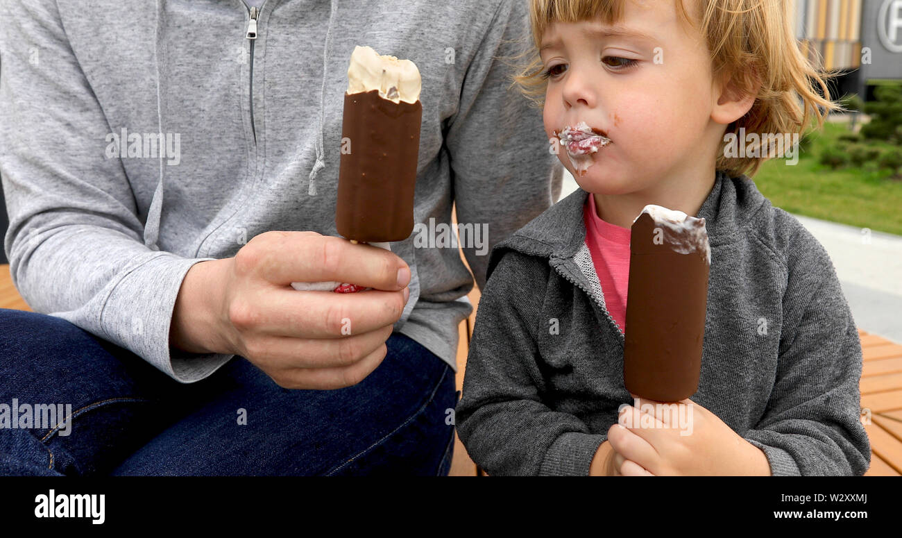 Dad and son eating ice cream on bench Stock Photo Alamy