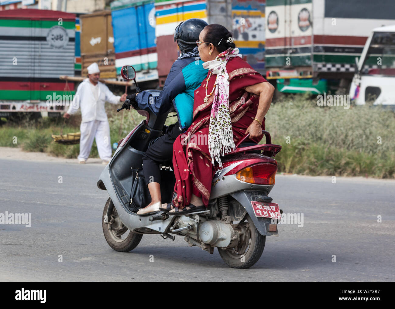 Two people on a scooter travelling along a road in Kathmandu Stock Photo