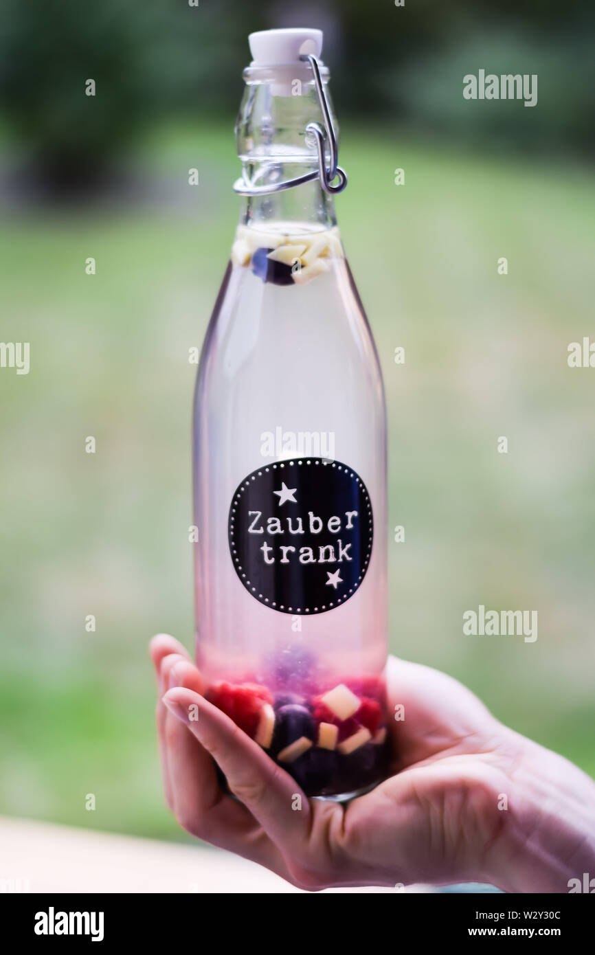 Hand hält Wasserflache mit Zaubertrank - Wasser mit Obst in Bügelflasche Stock Photo