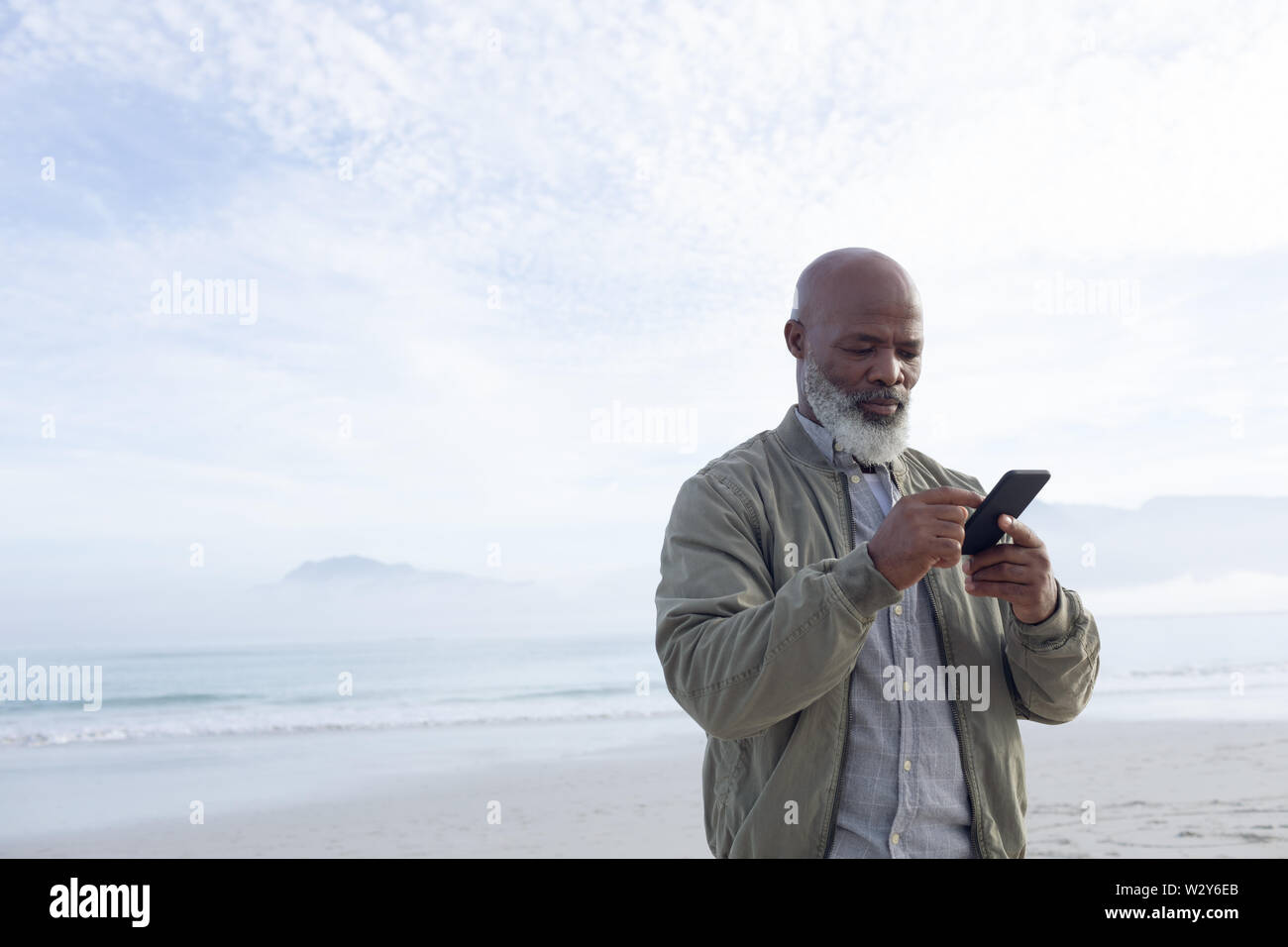 African-American man using a smartphone by the beach Stock Photo