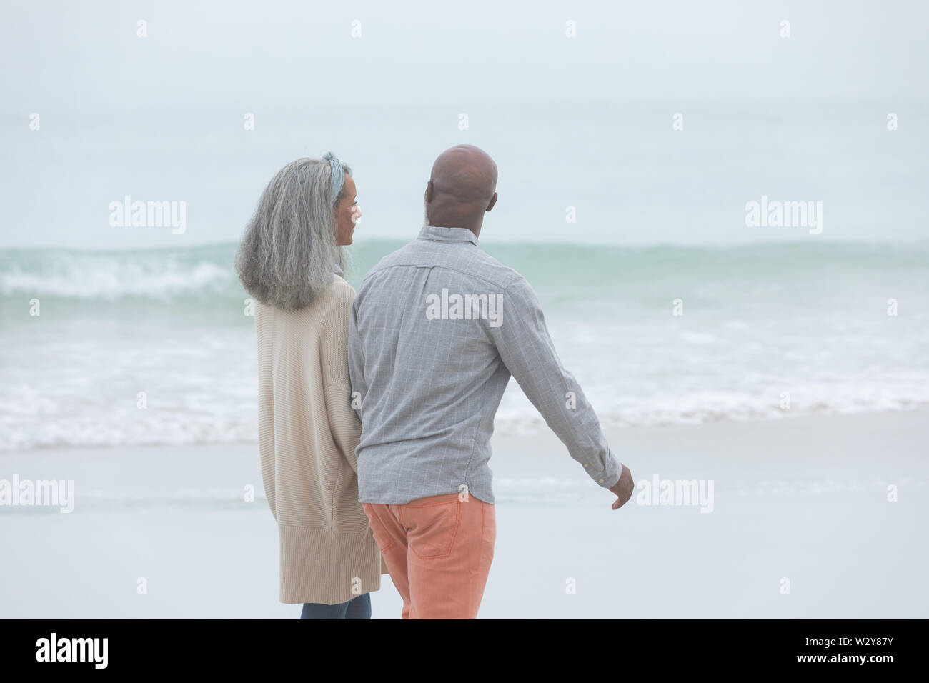 Couple holding hands while walking by the beach Stock Photo