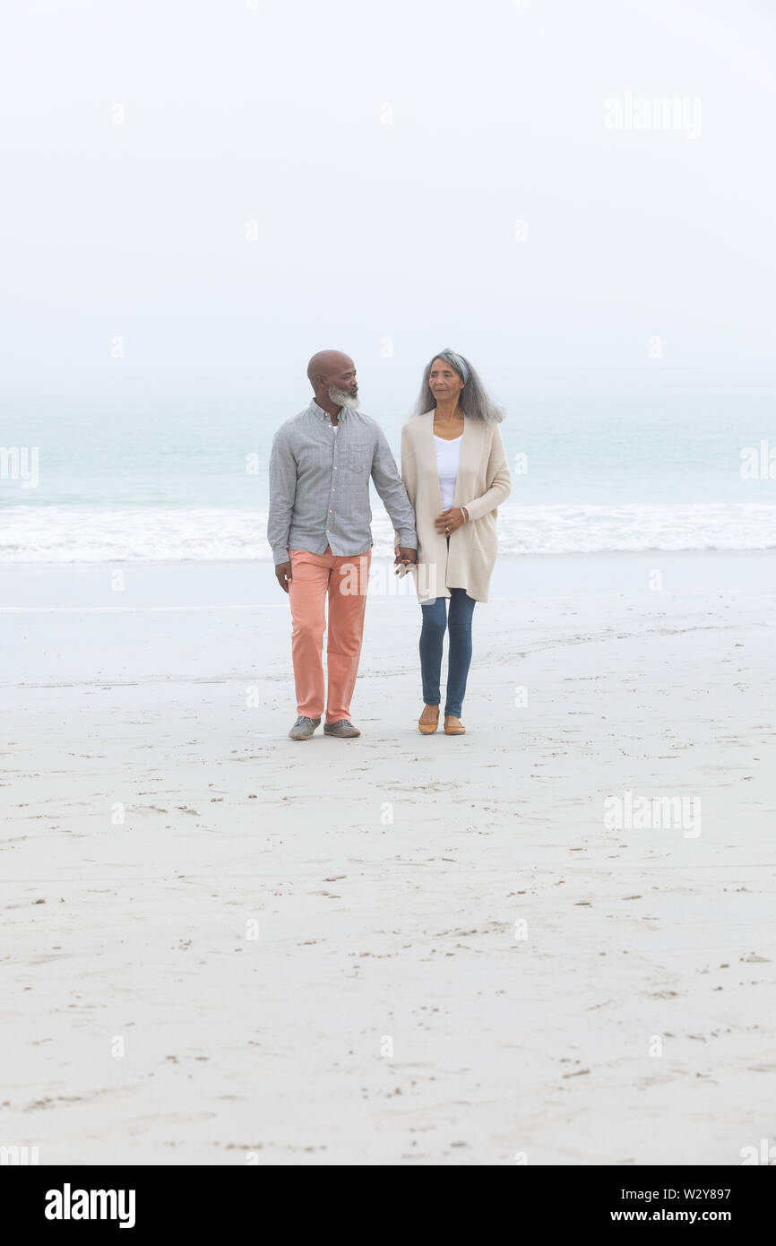 Couple holding hands while walking by the beach Stock Photo