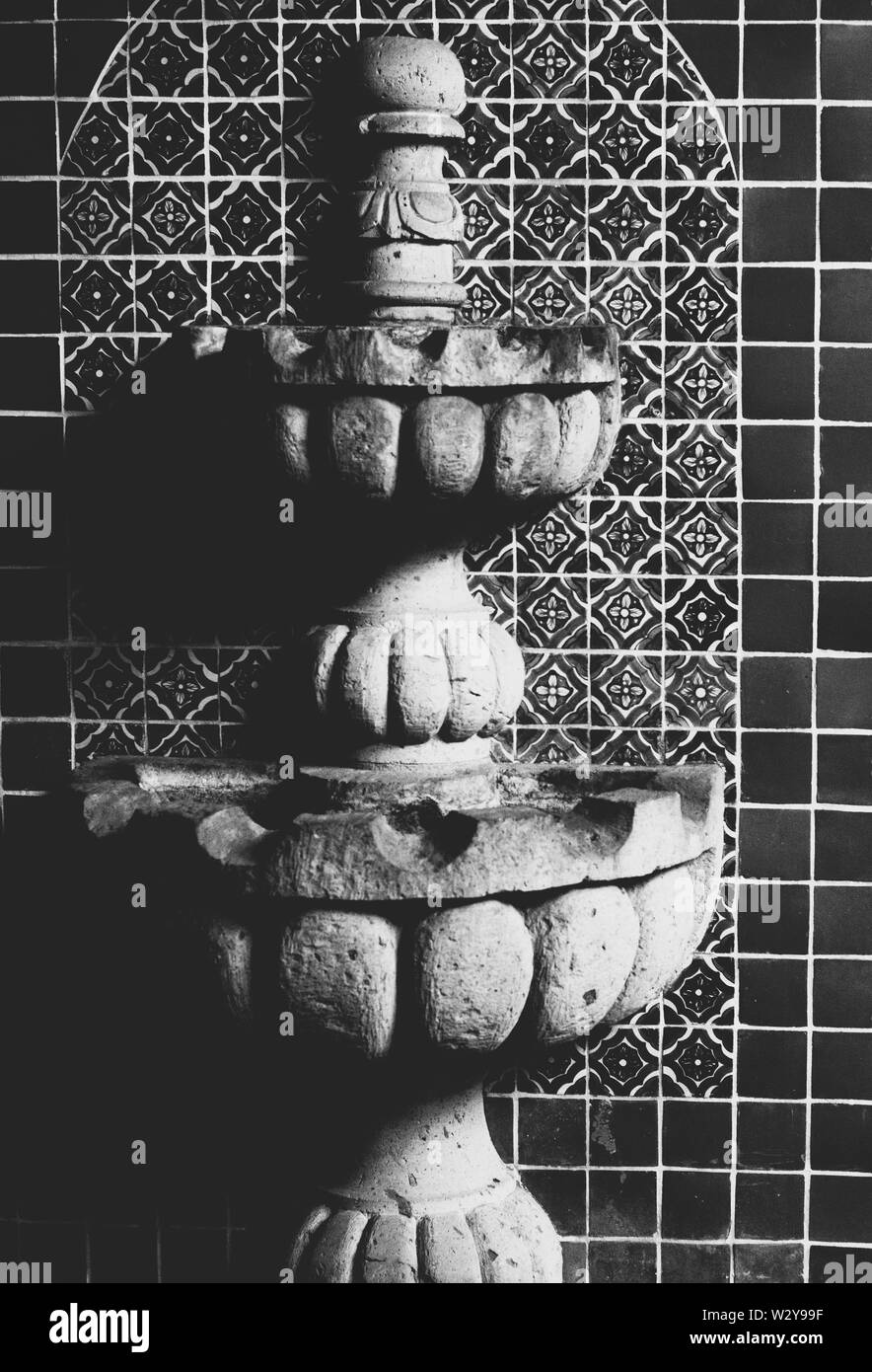 Closeup of a decorative indoors fountain on mosaic tiles shot in black and white Stock Photo