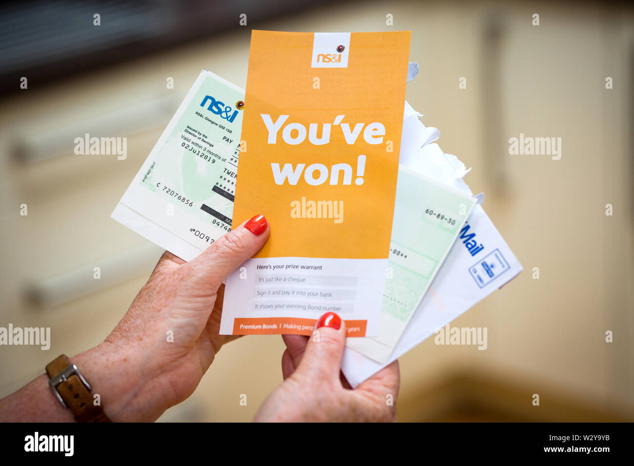 A woman opening a winning Premium Bonds letter with her winners cheque Stock Photo