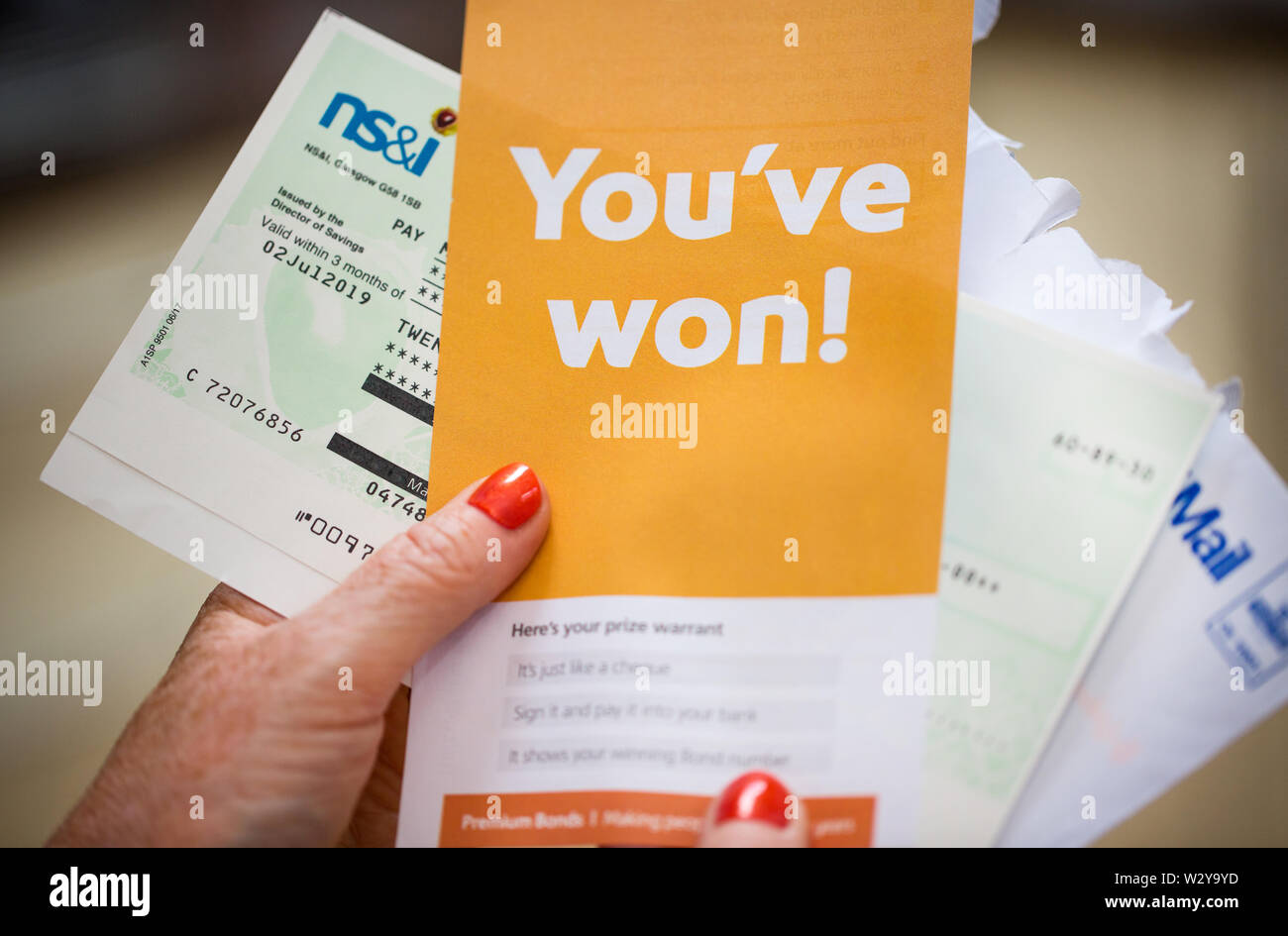 A woman opening a winning Premium Bonds letter with her winners cheque Stock Photo