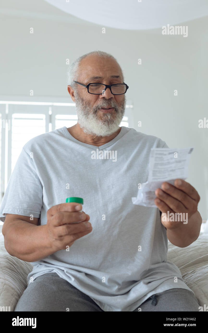 Man wearing glasses while sitting on bed Stock Photo