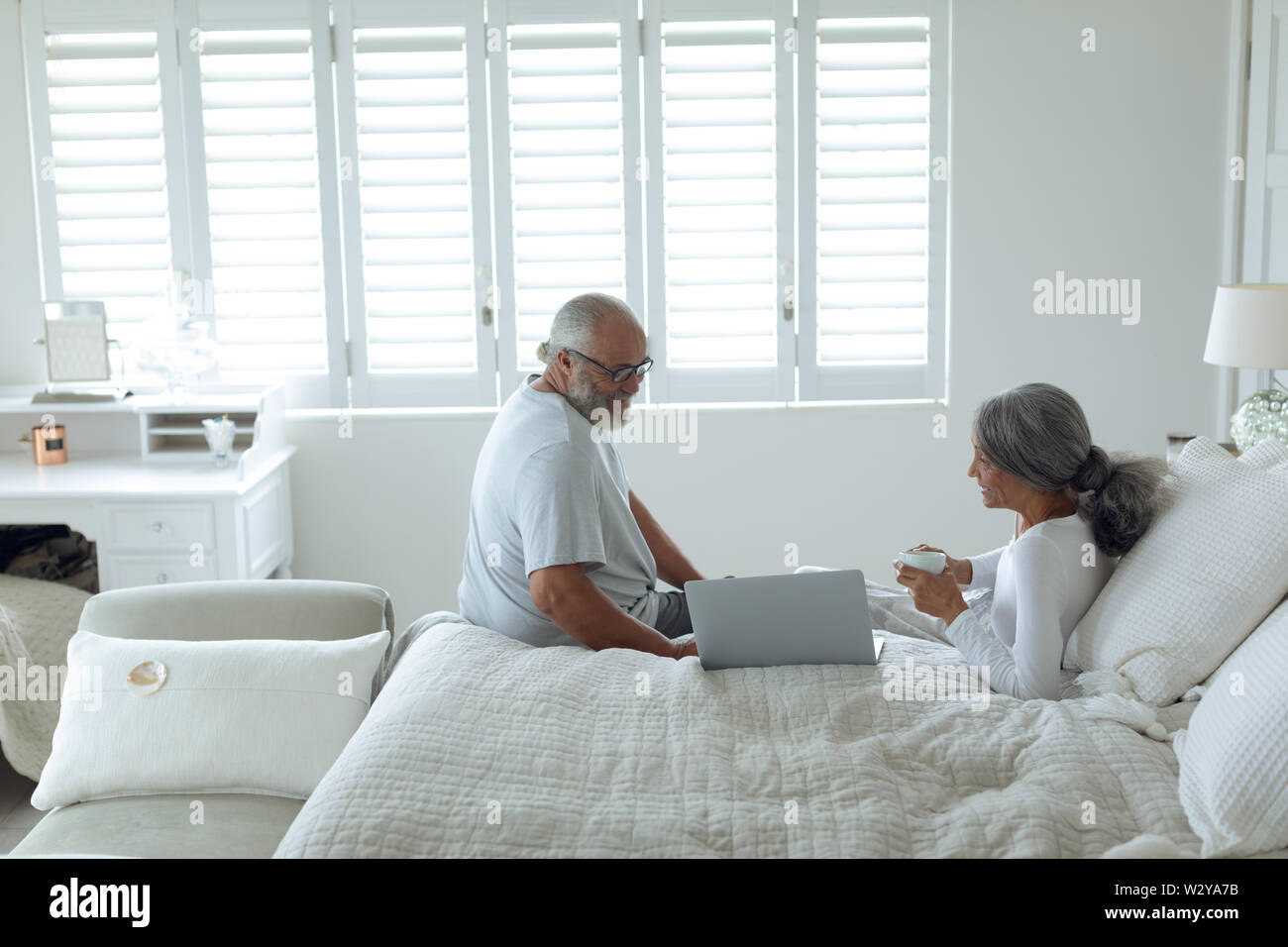Couple sitting on bed inside a room Stock Photo