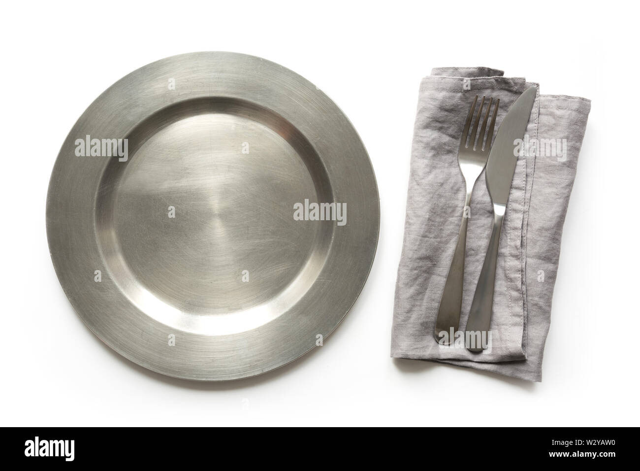 Empty metal dish with knife and fork on white table. Table setting. Stock Photo