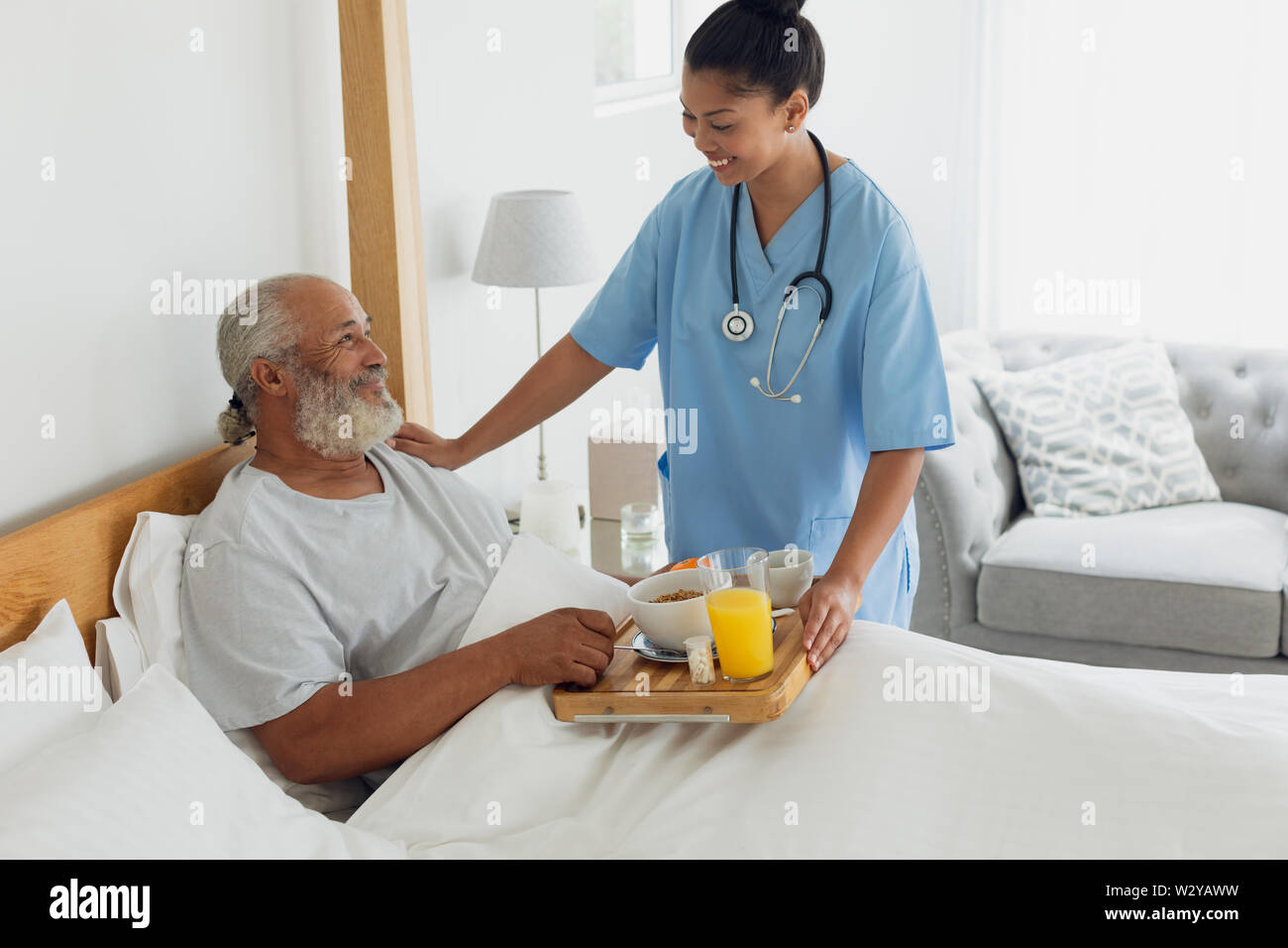 Healthcare worker talking with old man in bed Stock Photo