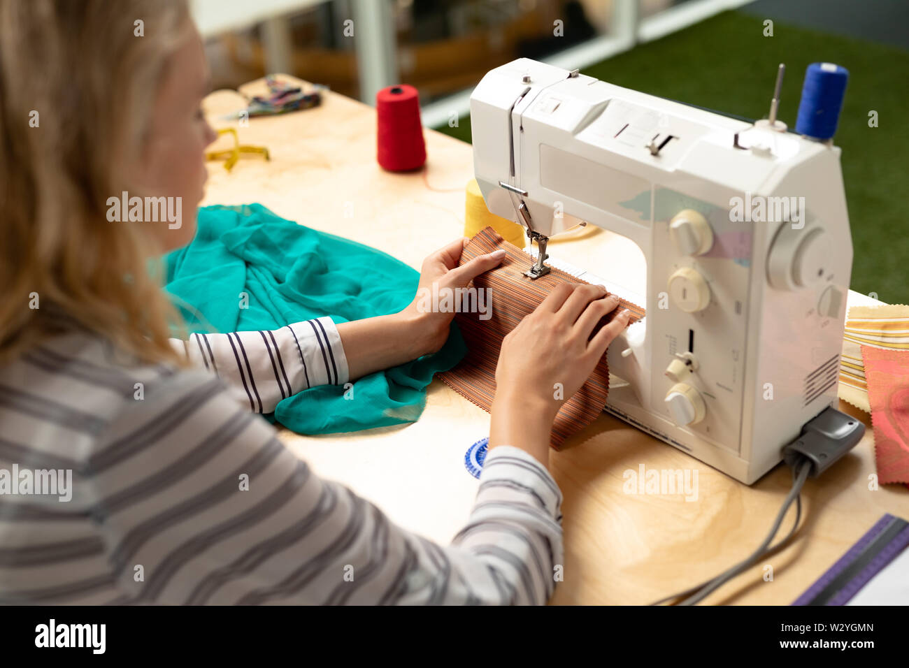 Female fashion designer using sewing machine on a table Stock Photo