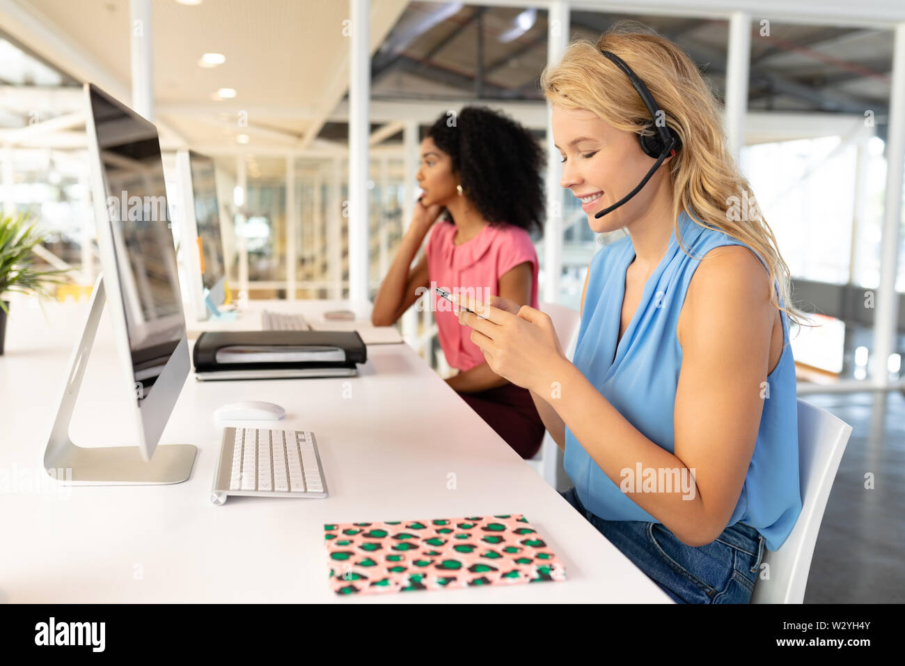 Female customer service executive using mobile phone at desk Stock Photo