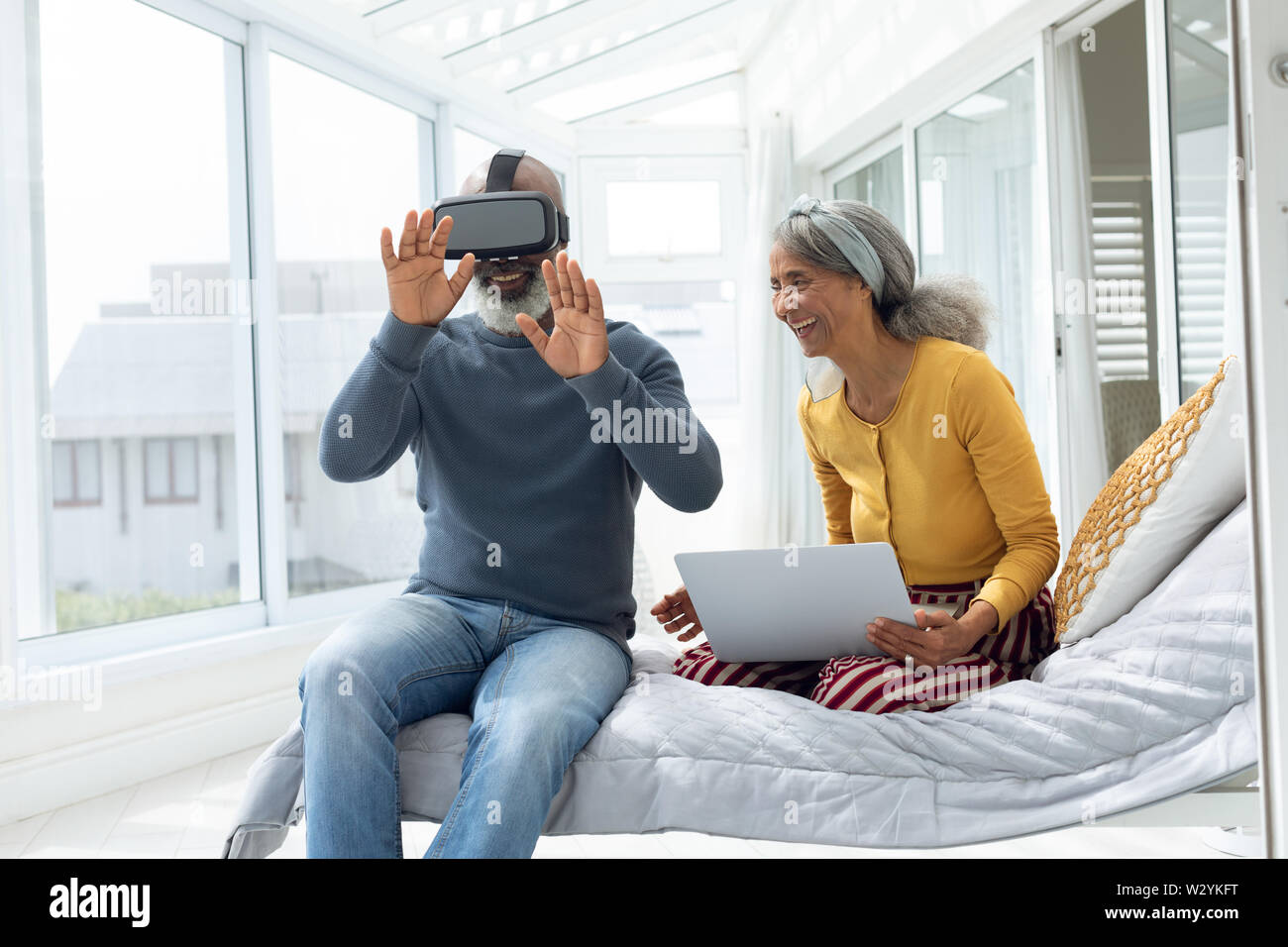 Couple sitting on bed while using digital devices Stock Photo