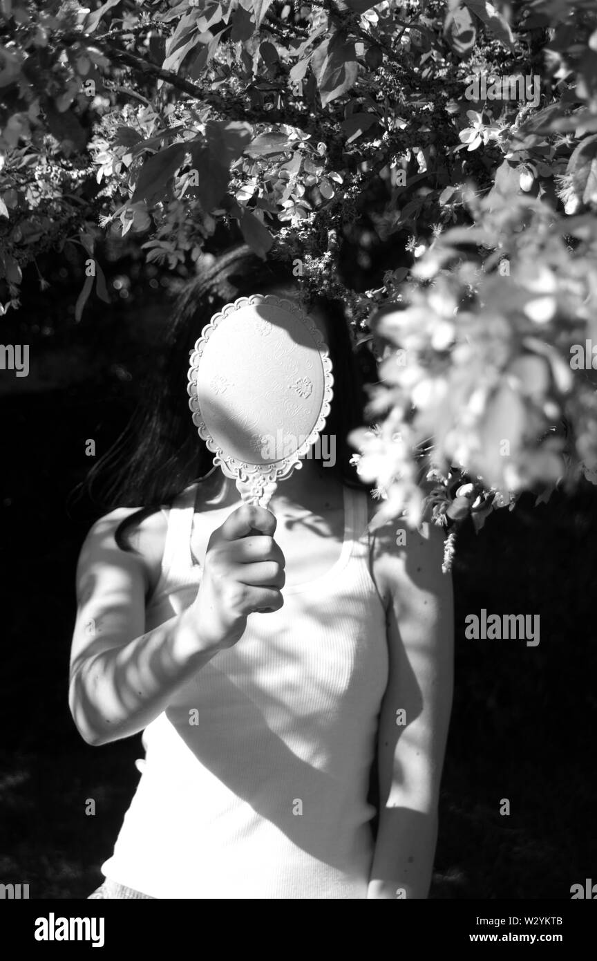 A self-portrait with a blossom tree and a mirror hiding my face. Stock Photo