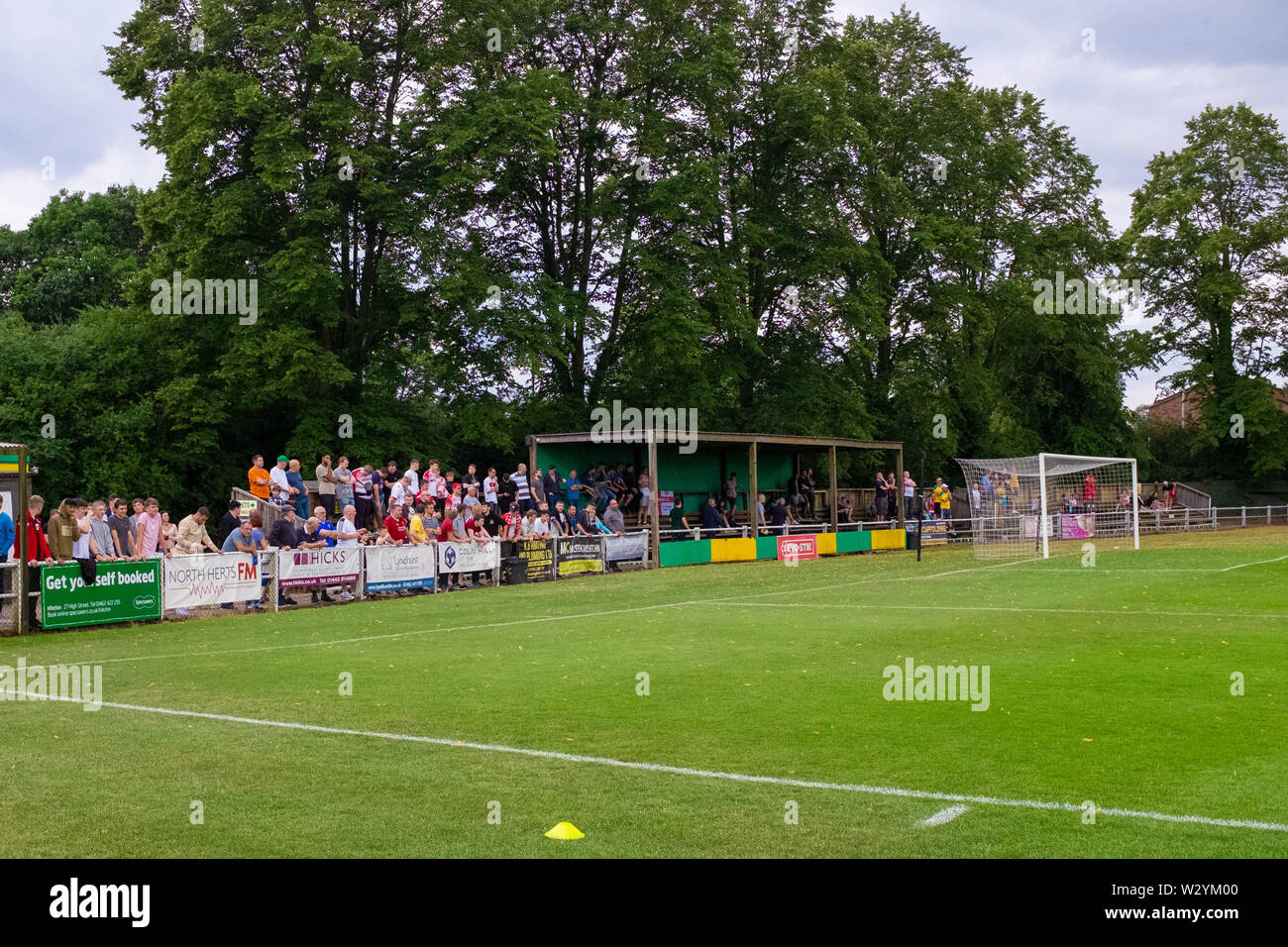Fans and spectators watching lower, non league football match from behind goal at Hitcin Town Football Club Stock Photo