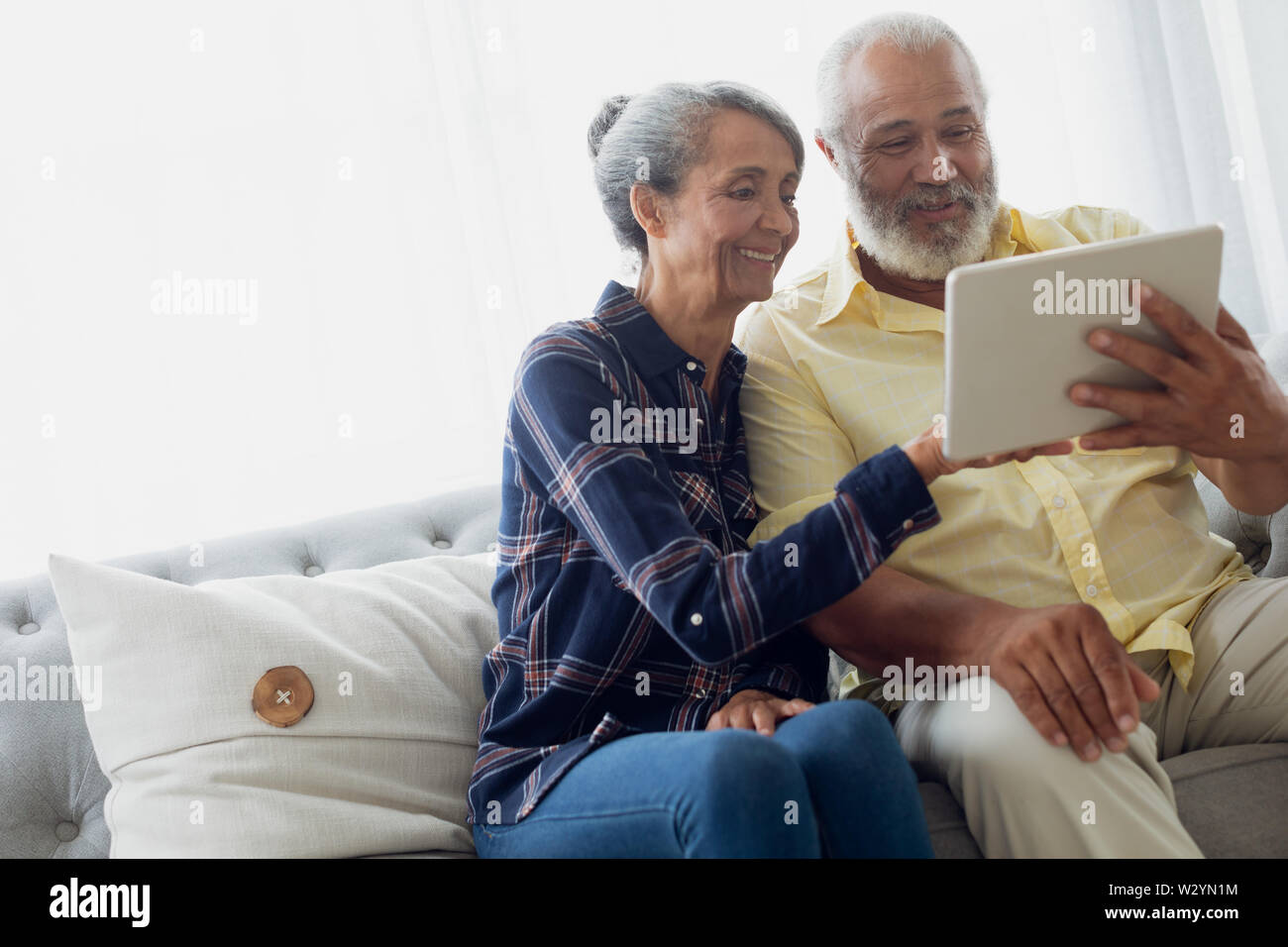 Couple sitting on couch while using a tablet Stock Photo