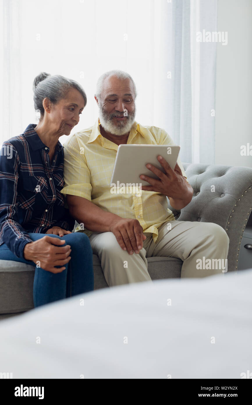 Couple sitting on couch while using a tablet Stock Photo