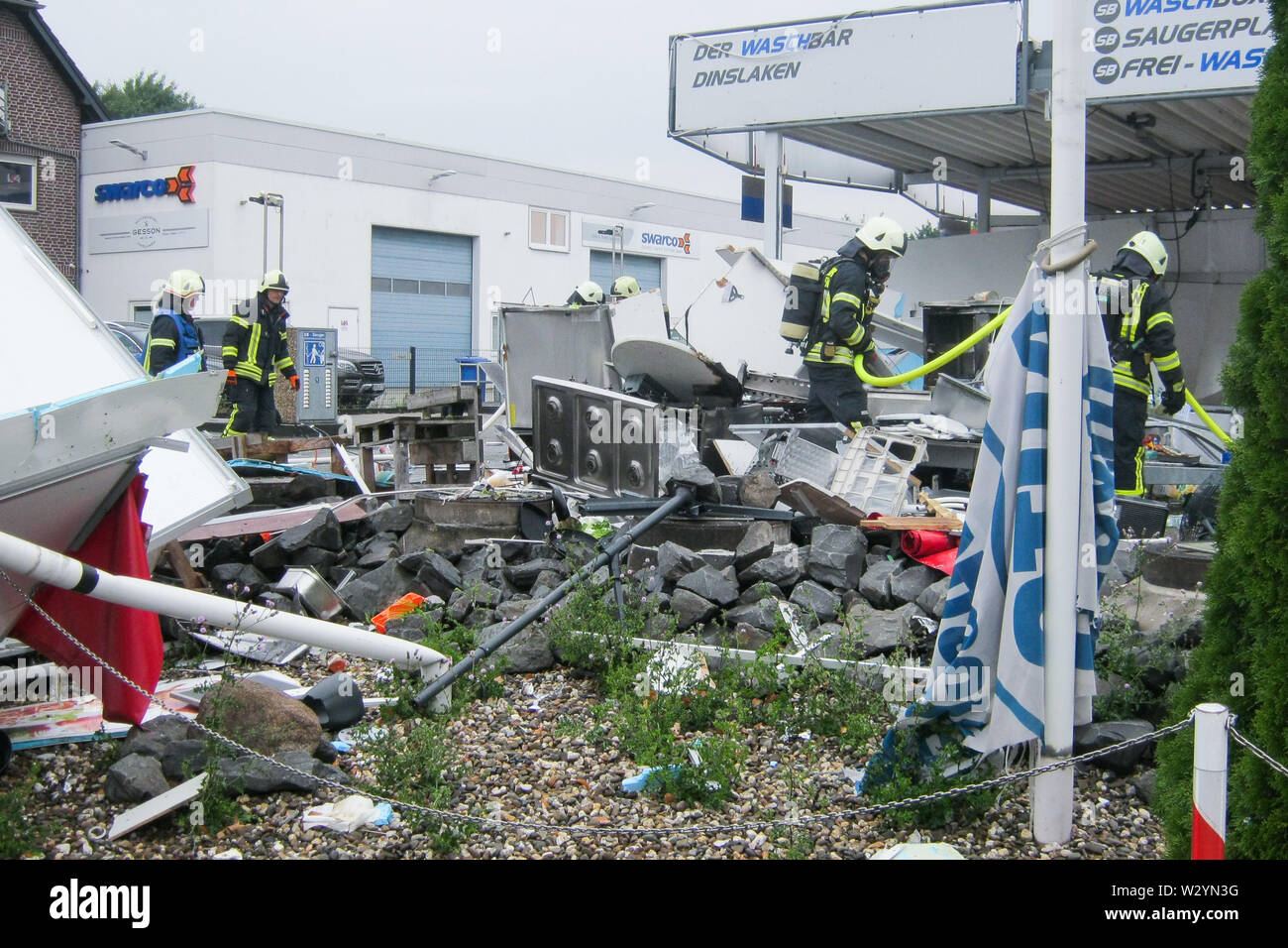 Dinslaken, Germany. 11th July, 2019. Firefighters are working on an exploded snack car. The pressure wave and debris damaged passenger cars and adjacent buildings. According to a spokesman for the fire brigade, the cause of the explosion could have been defective gas cylinders. Credit: Feuerwehr Dinslaken/dpa/Alamy Live News Stock Photo