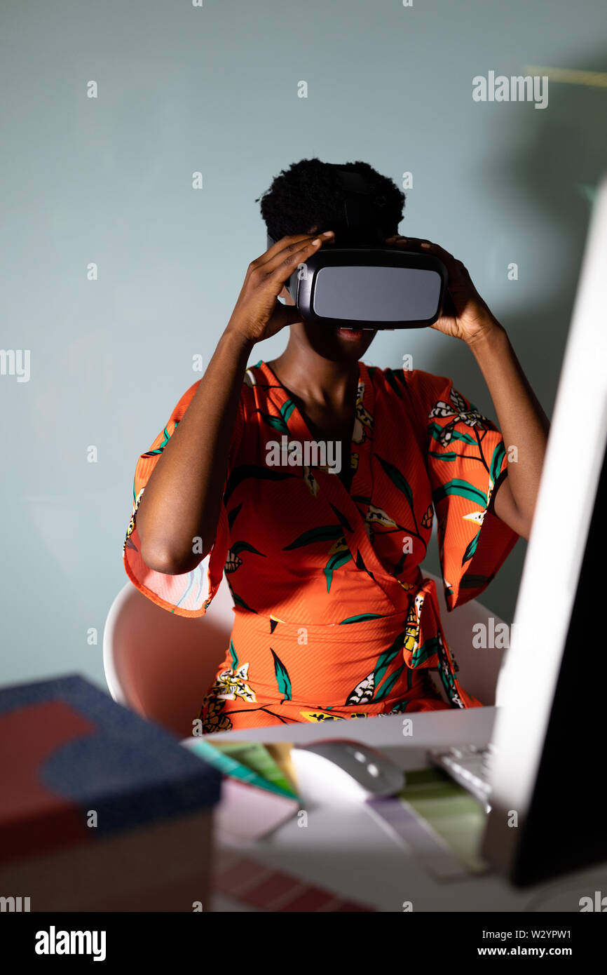 Female graphic designer using virtual reality headset at desk Stock Photo