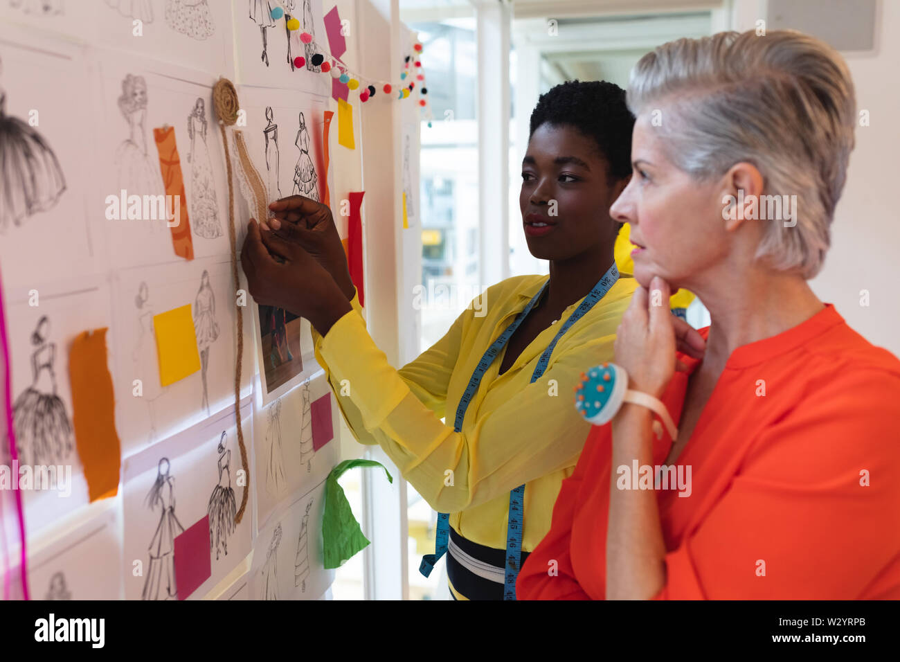 Female fashion designers discussing over sketch design Stock Photo