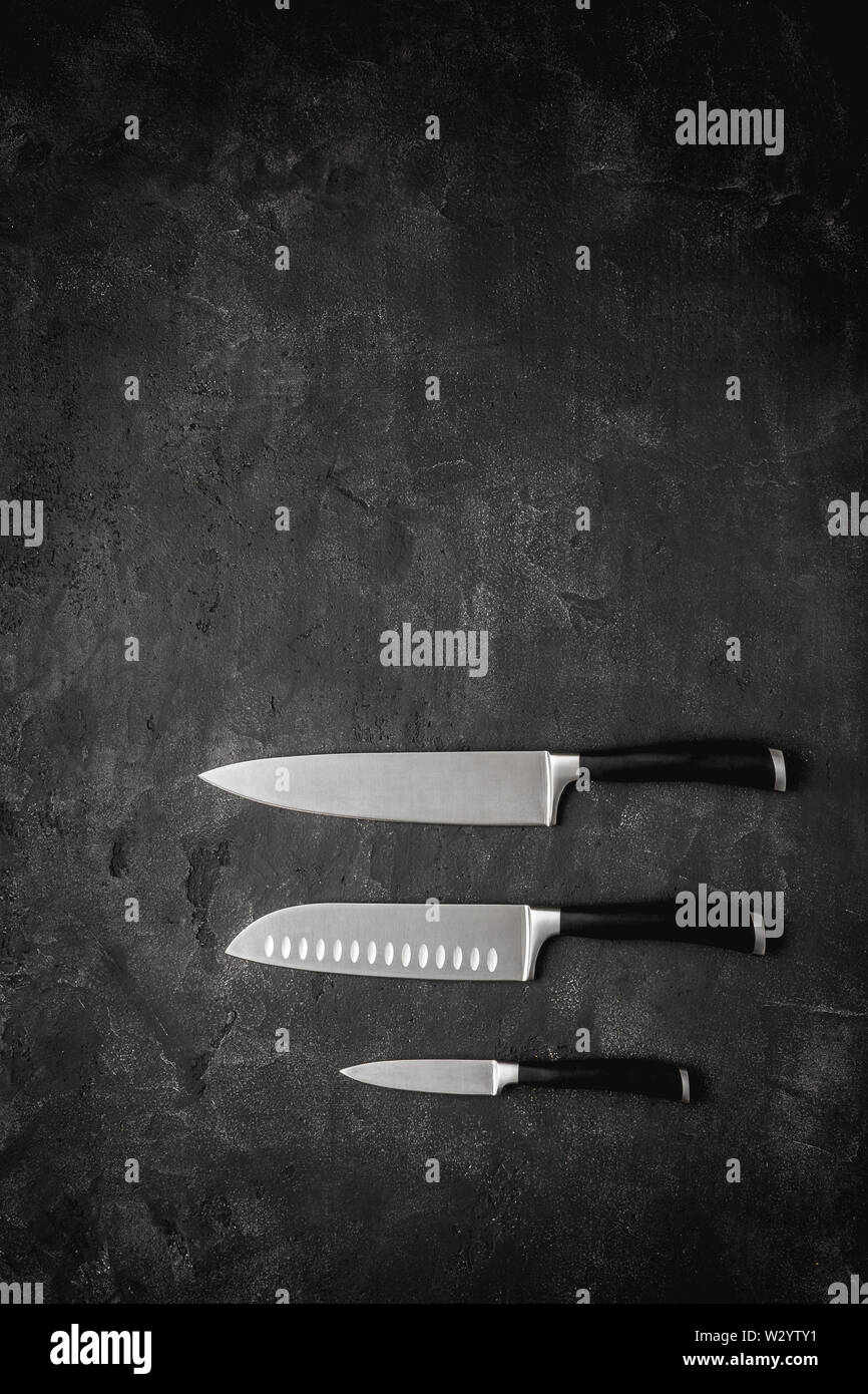 Modern Kitchen Knives Set on Dark Stone Background. Chef's Knives Concept. Stock Photo