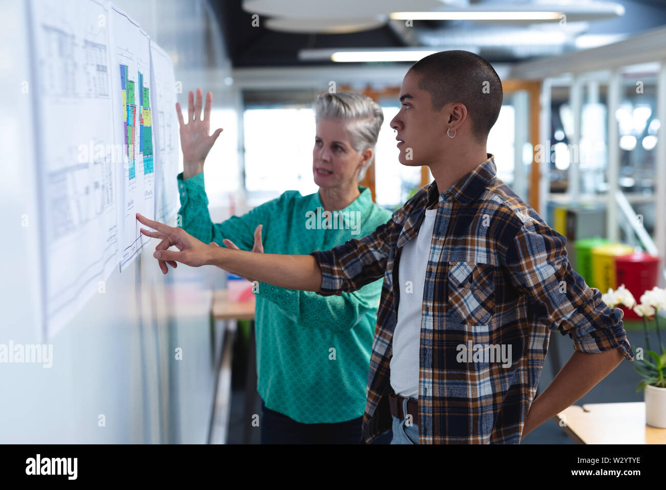 Male and female architects discussing over an architectural plan in office Stock Photo