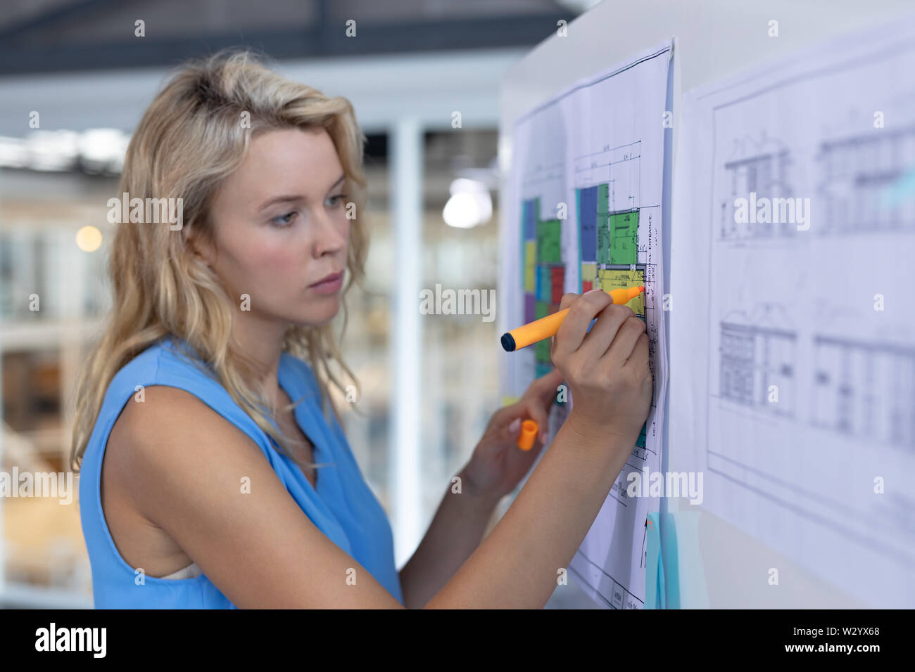 Female architect working over blueprint on whiteboard in a modern office Stock Photo