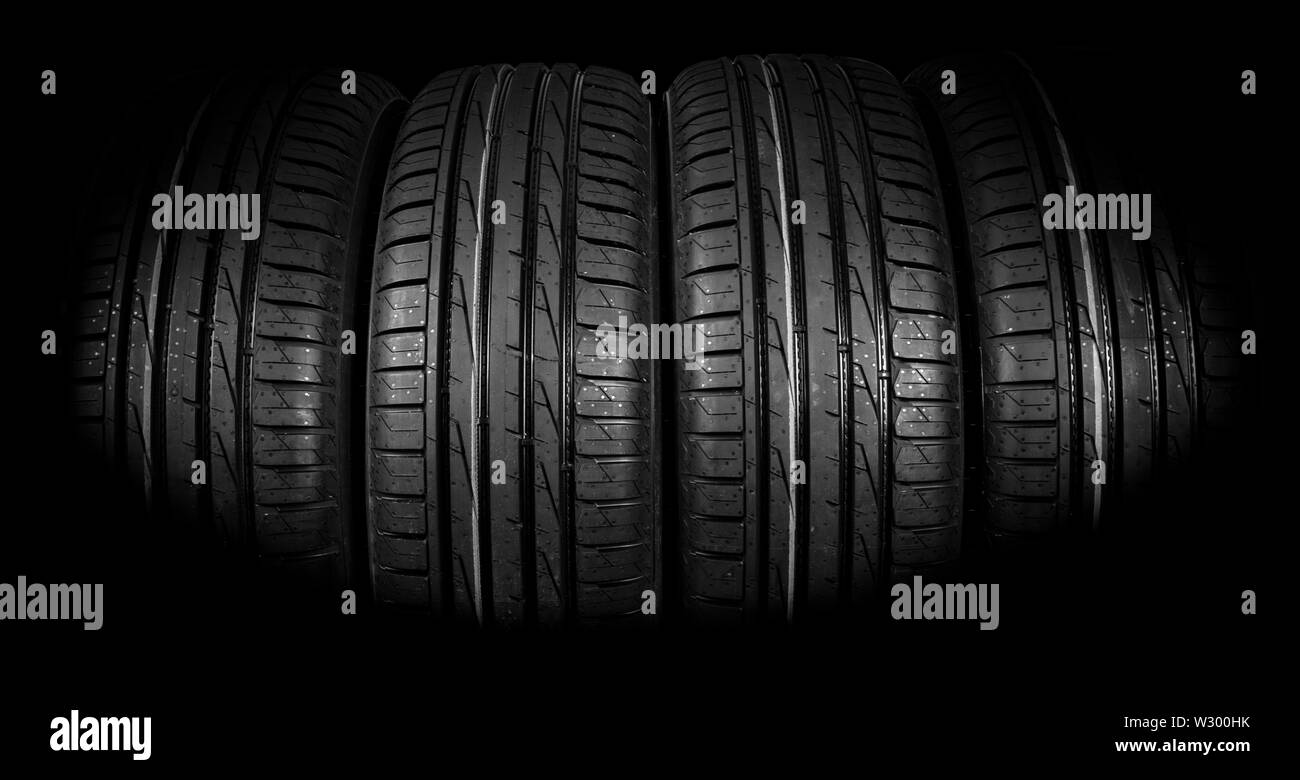 Studio shot of a set of summer car tires on black background. Tire stack background. Car tyre protector close up. Black rubber tire. Brand new car tir Stock Photo