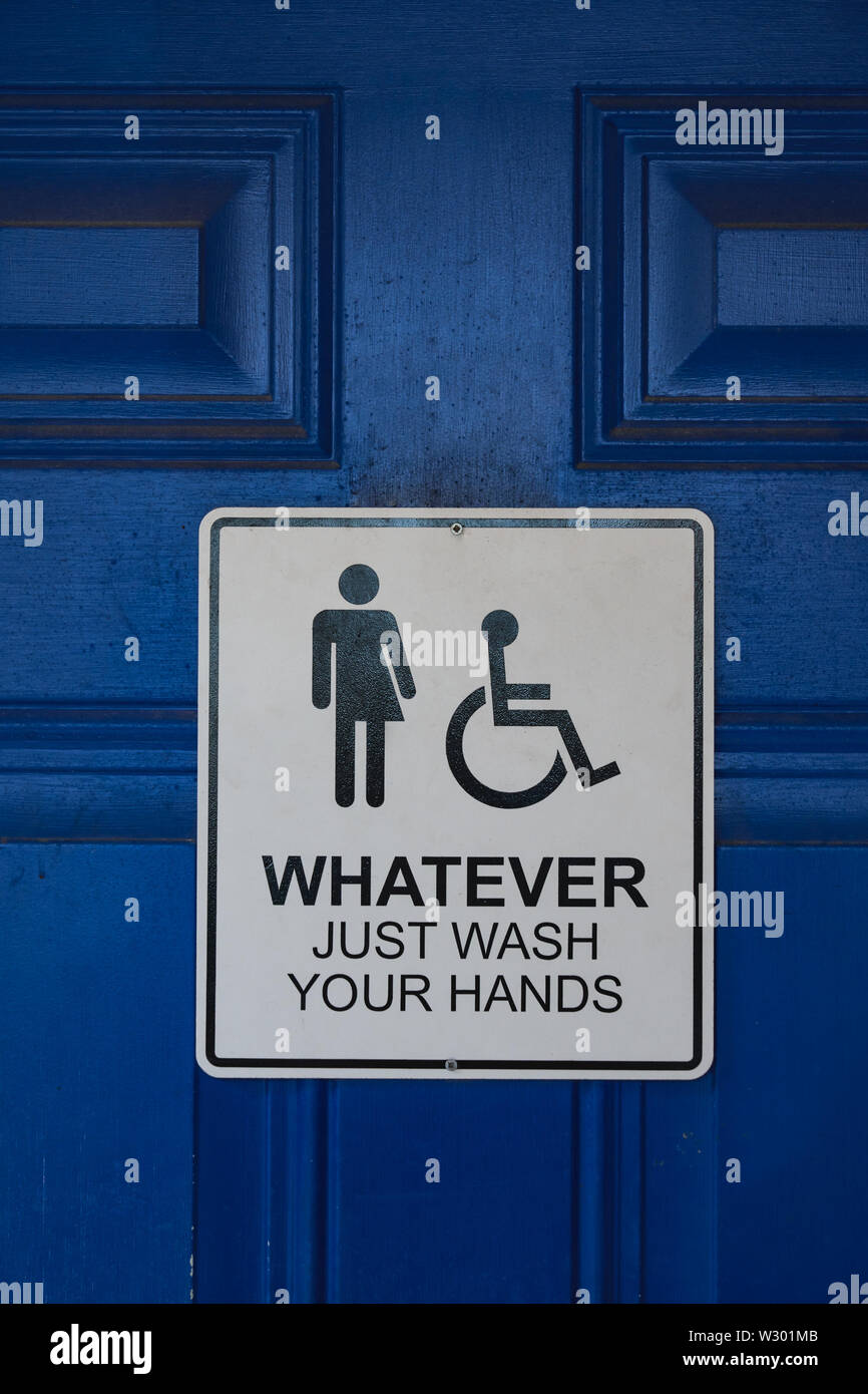Sign on a blue restroom door says 'Whatever Just Wash Your Hands' and includes male, female, and handicapped symbols Stock Photo