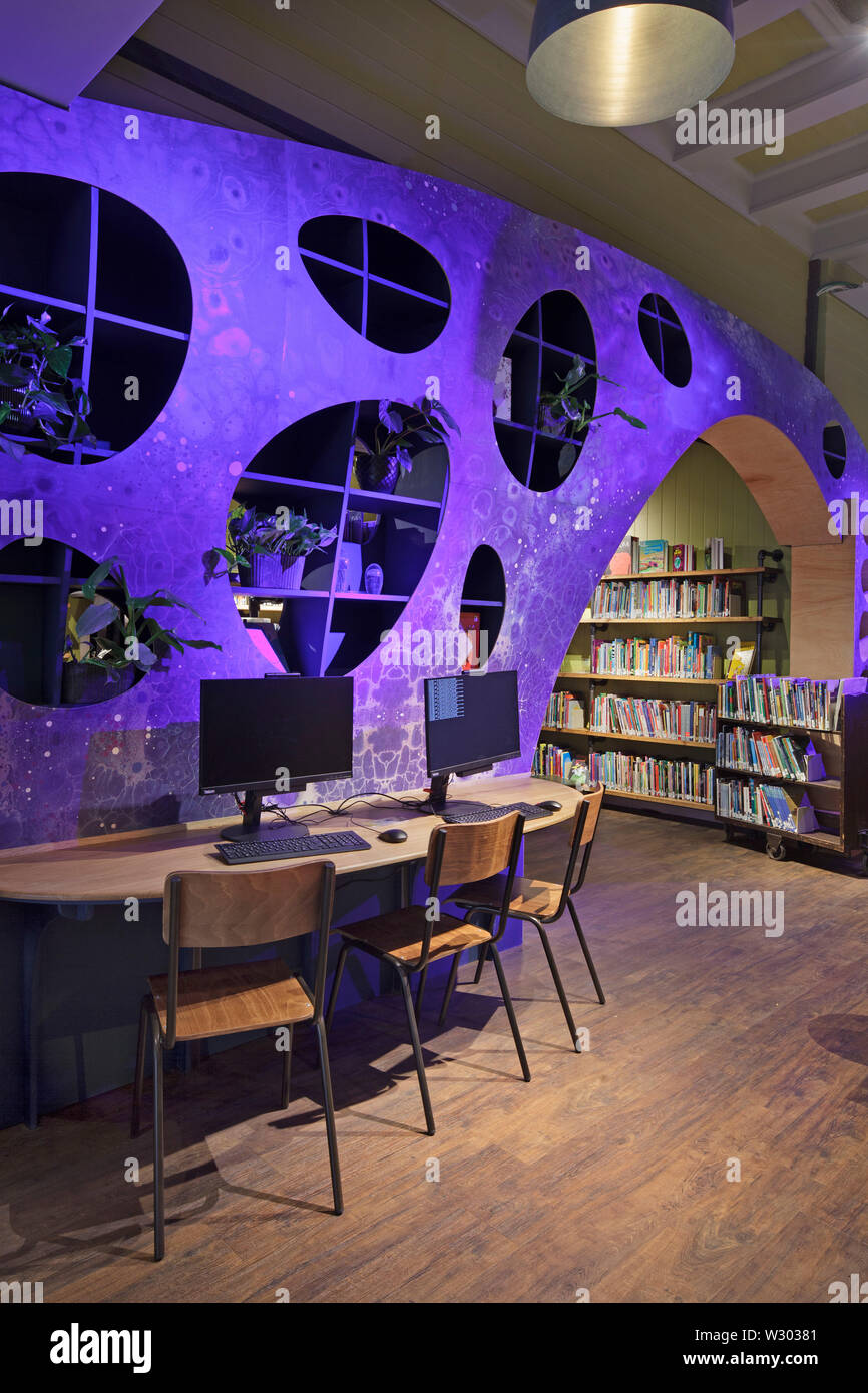 Purple spotlit wave-form wall section in children's library. Deichman Library Grunerlokka, Oslo, Norway. Architect: Aat Vos, 2019. Stock Photo