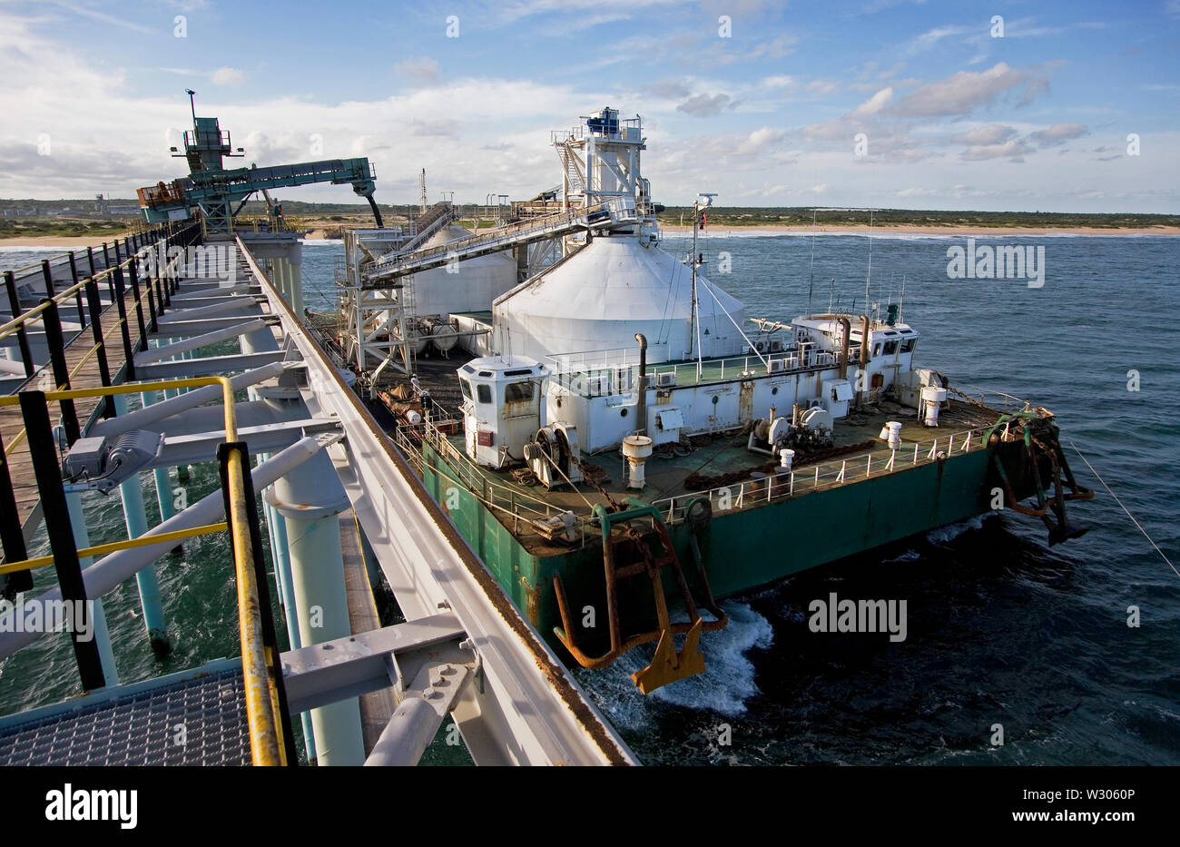 Mining, managing & transporting of titanium mineral sands. Port operations with barge loading & marine jetty work before transhipping product to OGV. Stock Photo