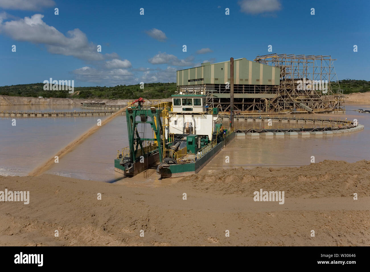 Managing & transporting of titanium mineral sands at mine site. Mining by dredging in freshwater ponds. Dredges pump sand into wet concentrator plant. Stock Photo