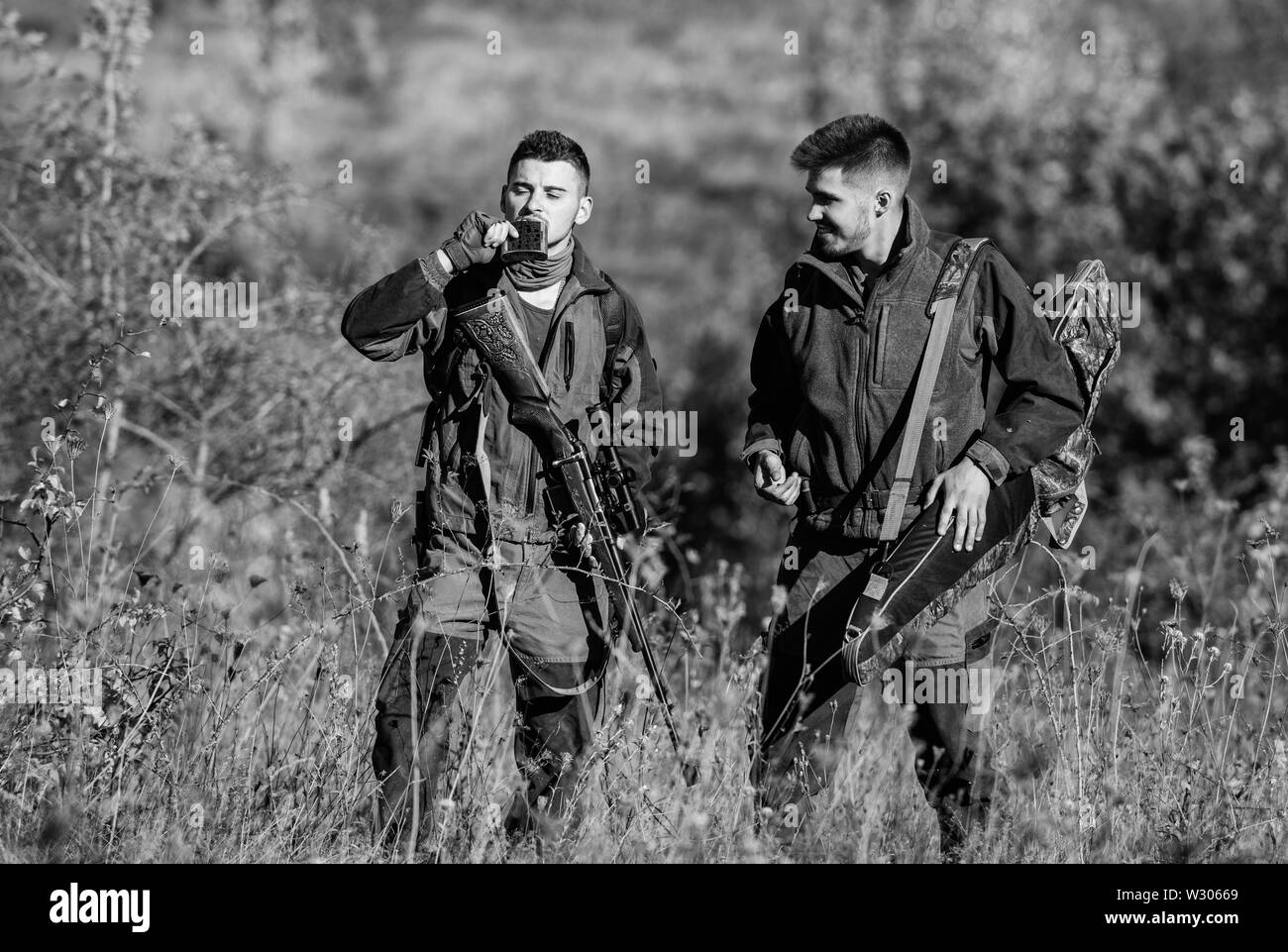 Man hunters with rifle gun. Boot camp. Hunting skills and weapon equipment. How turn hunting into hobby. Military uniform fashion. Friendship of men hunters. Hunter aiming rifle in forest. Stock Photo