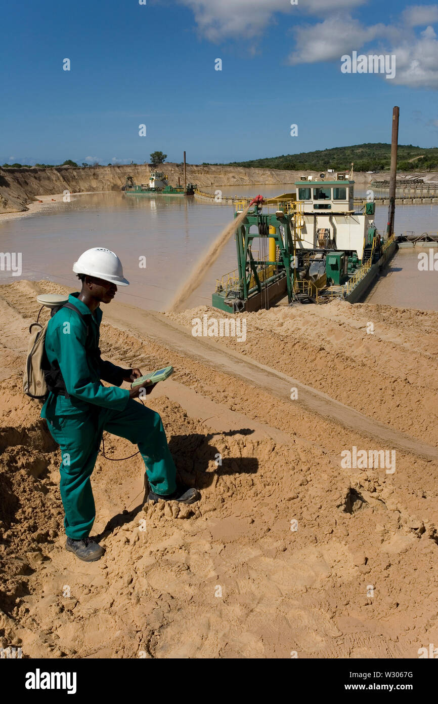 Managing & transporting of titanium mineral sands at mine site. Mining using dredges pumping sand from water ponds & surveyor measuring dune heights. Stock Photo