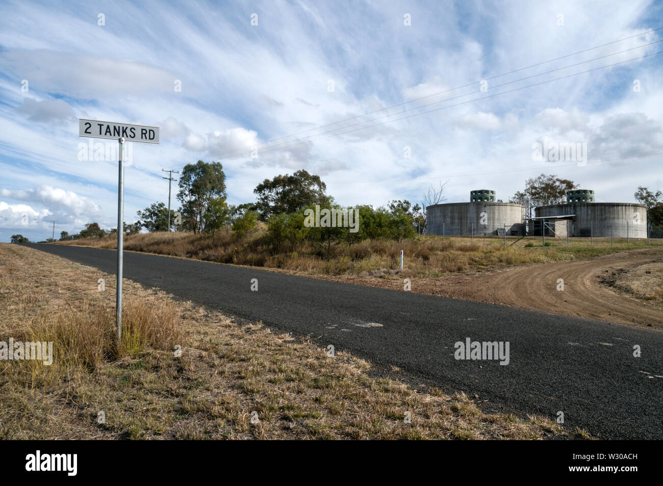 A road sign pointing to 2 Tanks road with two tanks on a site in Springsure, Queensland Central