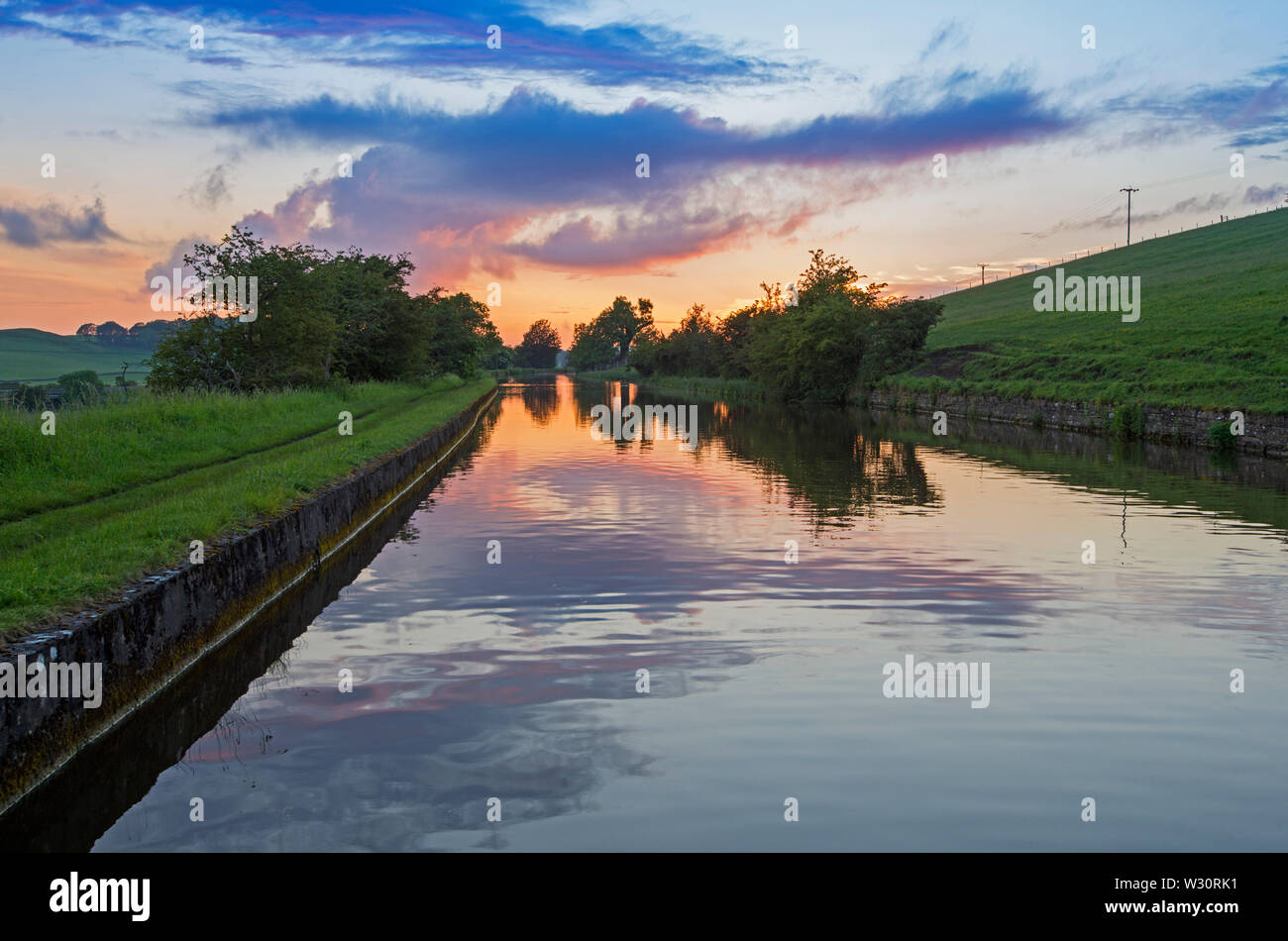 View of an English rural countryside scenery on British waterway canal during cloudy day at sunset dusk Stock Photo