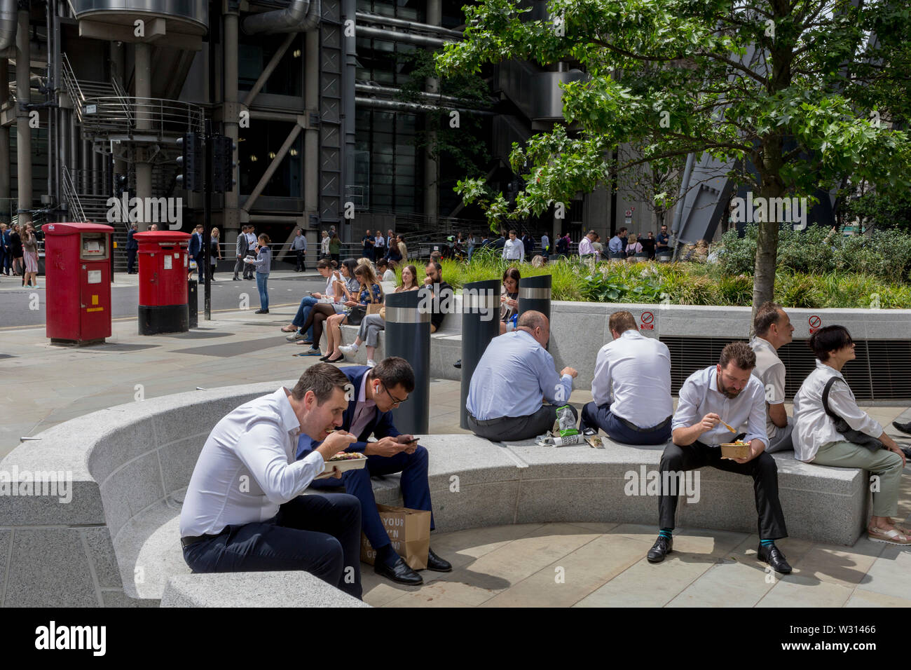 Lunchtime crowds eat takeaways in summer sunshine in Leadenhall in the City of London, the capital's financial district (aka the Square Mile), on 10th July 2019, in London England. Stock Photo