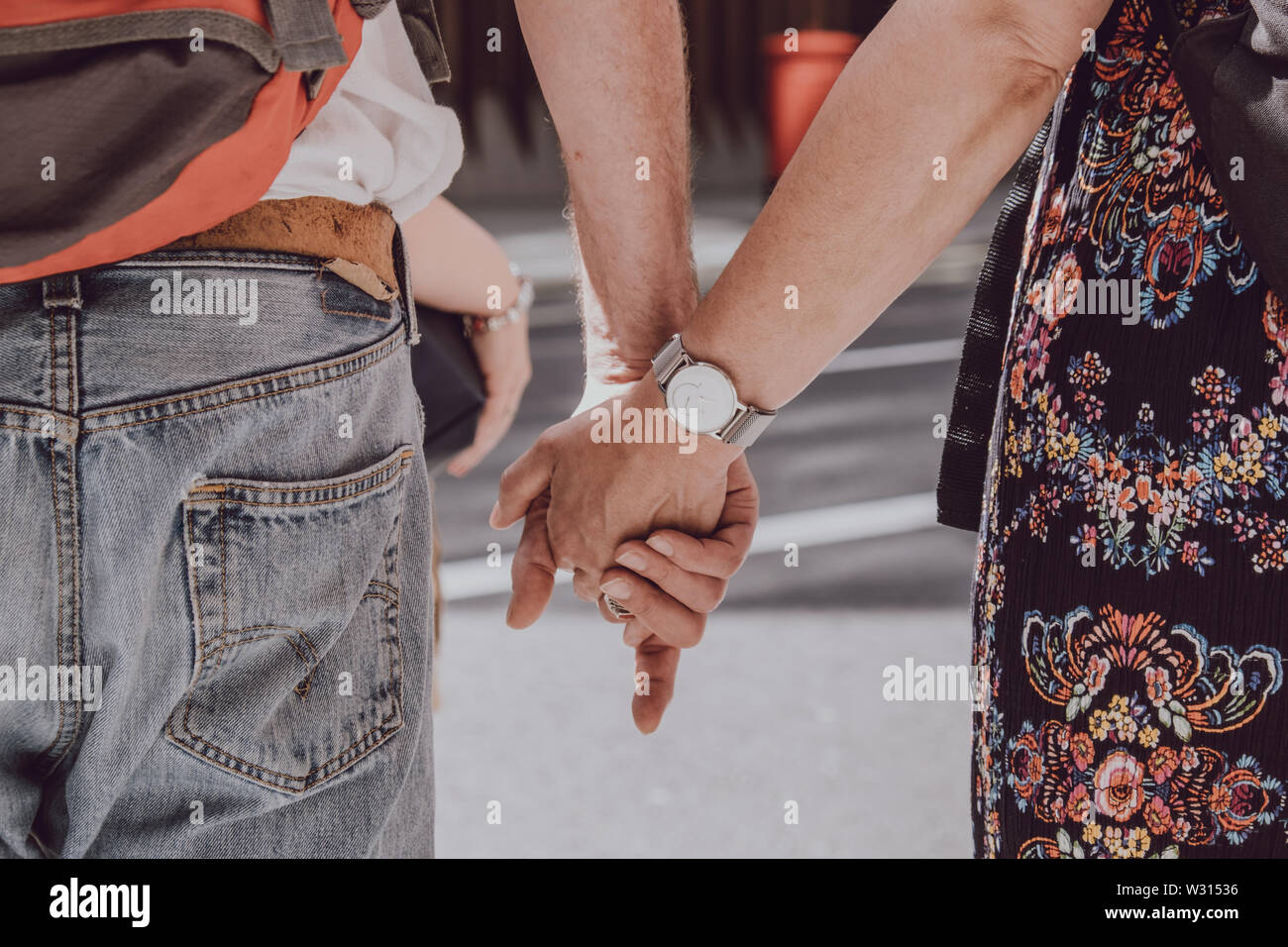 Close up of unidentified Caucasian couple holding hands in public, love concept, selective focus. Stock Photo