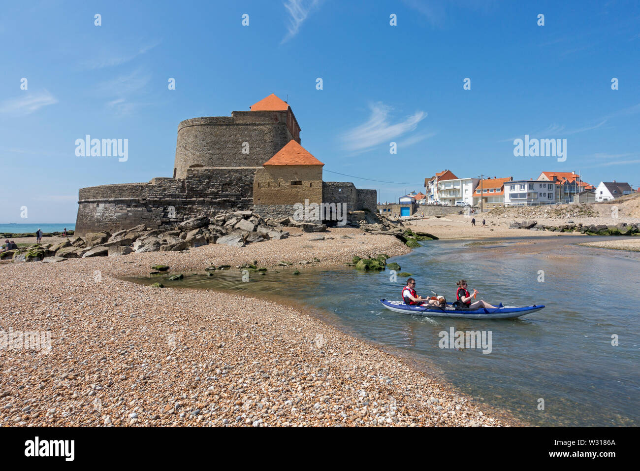 Tourists in kayak in front of Fort Mahon and shingle beach at Ambleteuse along rocky North Sea coast, Côte d'Opale / Opal Coast, France Stock Photo