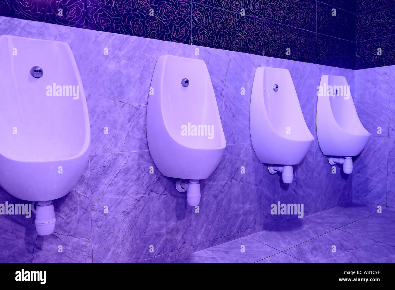 Urinals in the toilet on the wall hanging in a row Stock Photo