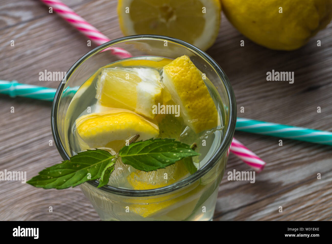Lemonade with fresh lemon, ice and mint on wooden background. Cool drink at summer time. Stock Photo