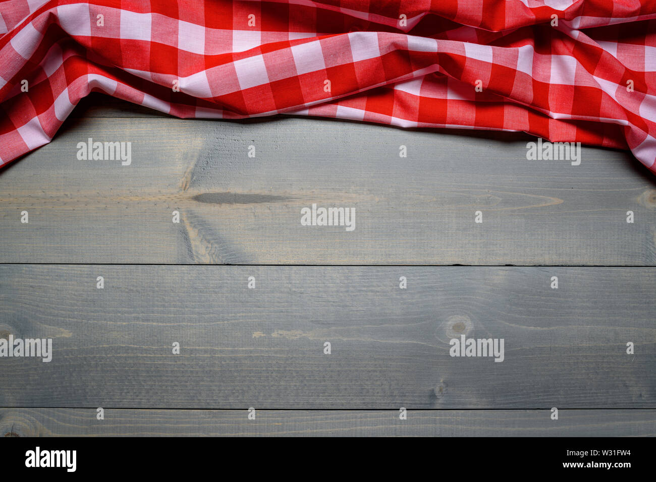 a checked gingham picnic tablecloth on old wooden table top view Stock Photo