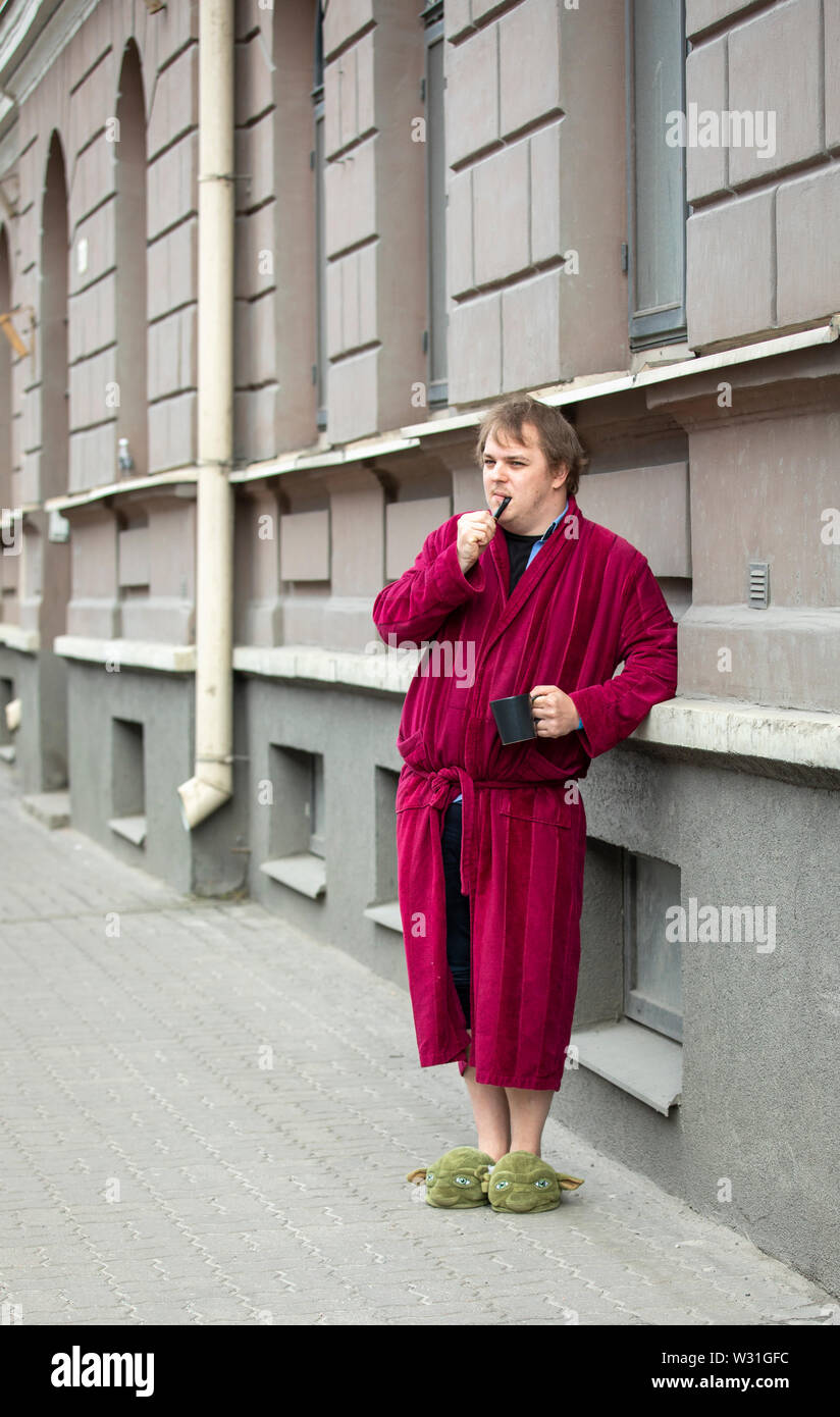 tallinn-estonia-6th-july-2019-man-in-a-bathrobe-in-a-street-smoking-pipe-and-drinking-coffee-W31GFC.jpg