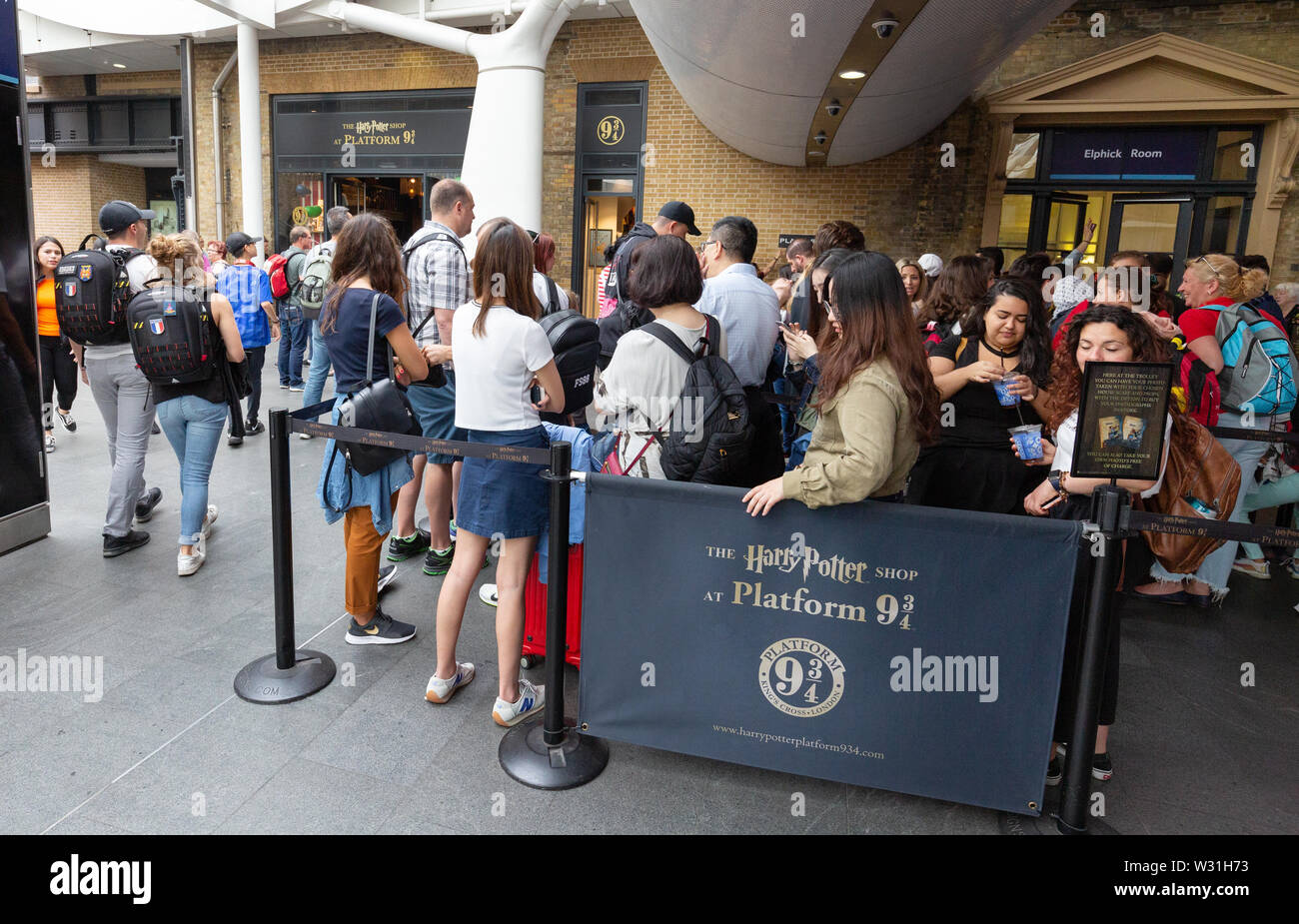 Harry Potter fans queuing in a queue outside the Kings Cross Station Harry Potter shop at Platform 9 3/4, Kings Cross Rail station, London UK Stock Photo