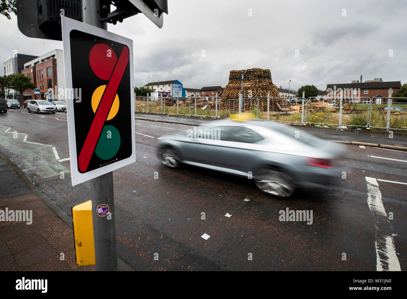 A missing traffic light on the pedestrian crossing on Shankill Road in Belfast, at its junction with Boundary Street, which is removed annually around 11 July to prevent any damage occurring due to the proximity of the nearby 11th night bonfire. The signal heads are re-erected as soon as possible after the event, with pedestrians advised to use the nearest alternative crossing facility at Craven Street Stock Photo